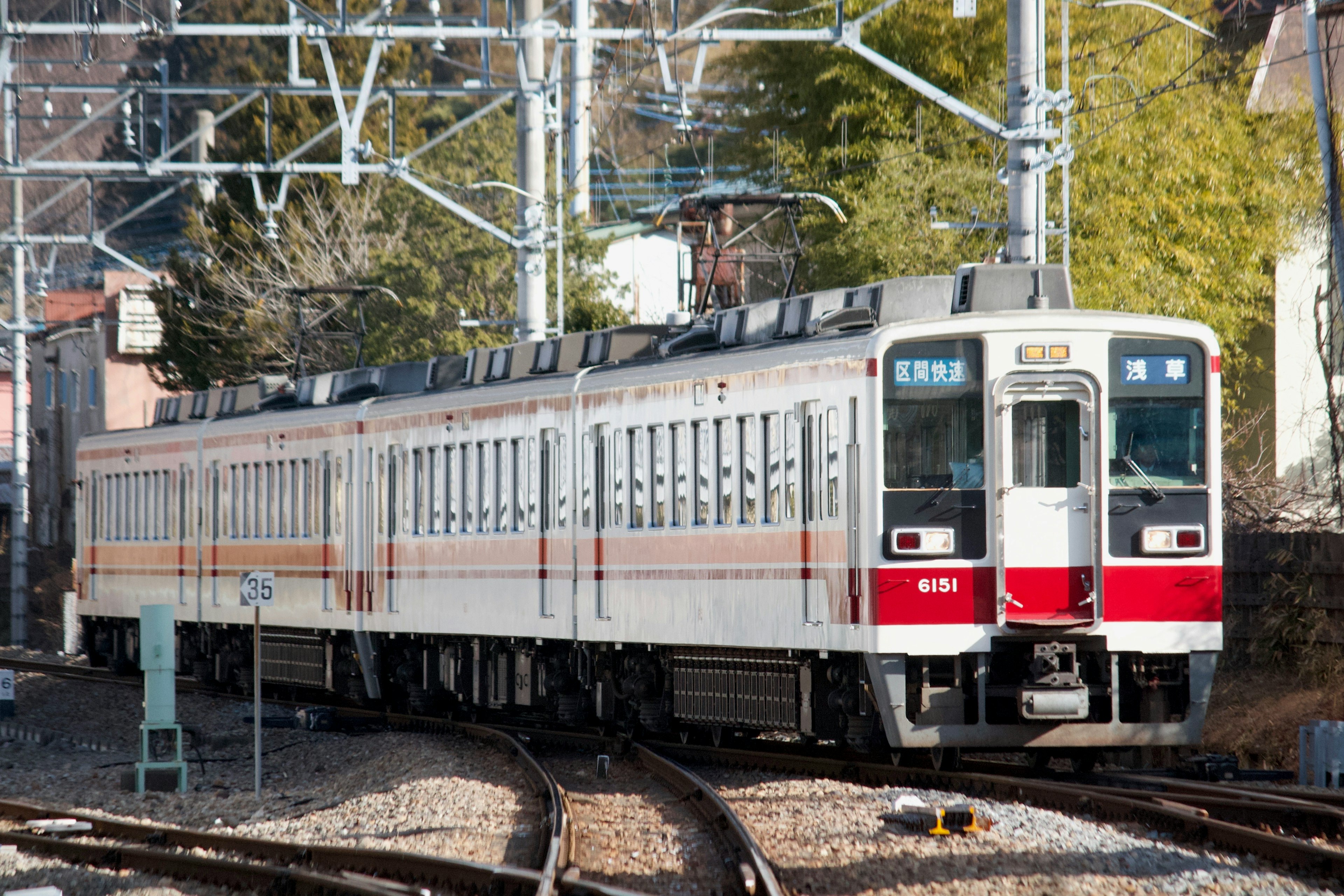 Un train blanc et rouge est arrêté à un croisement ferroviaire