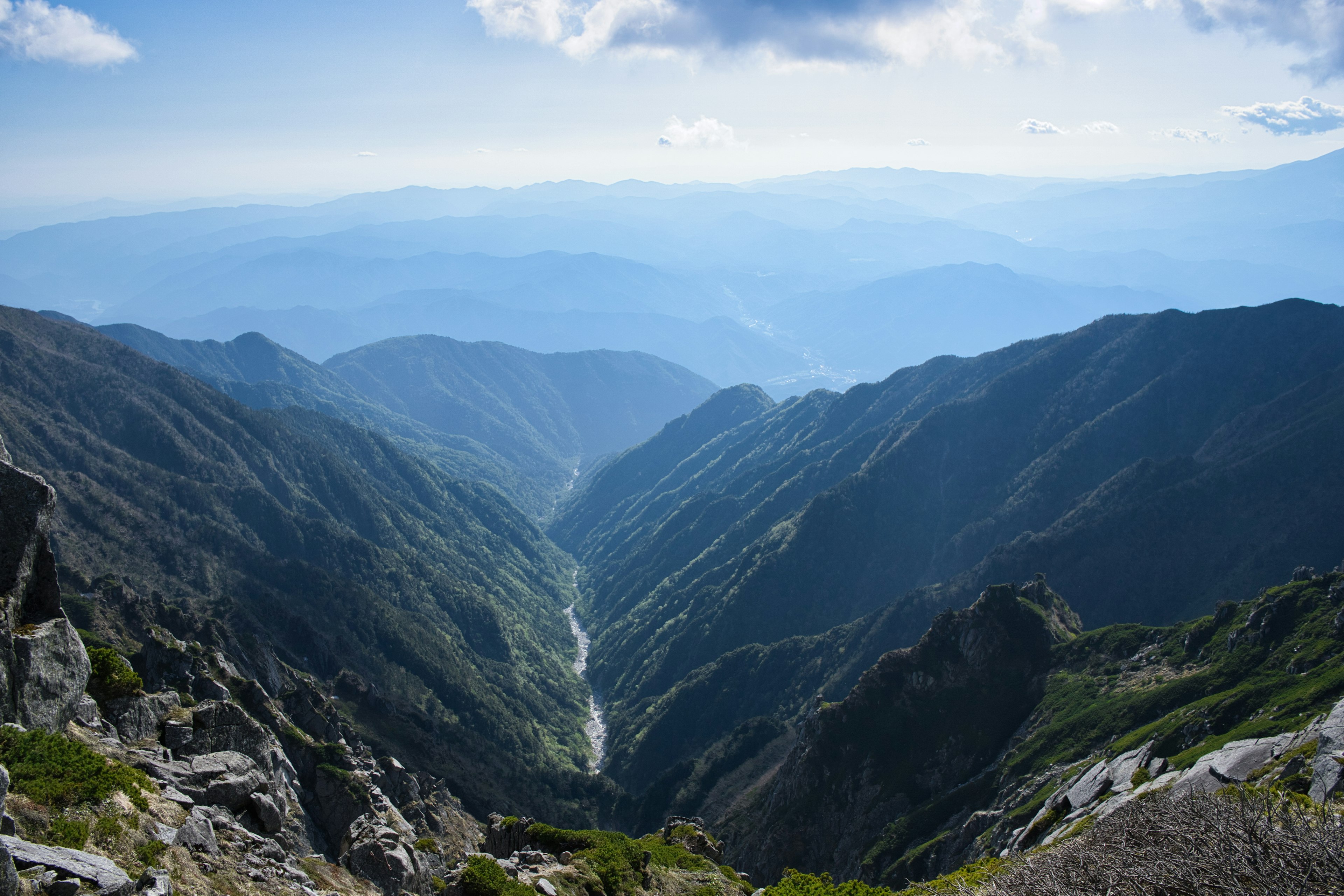 Atemberaubende Aussicht auf ein Gebirgstal mit zerklüfteten Gipfeln und fernen Horizonten