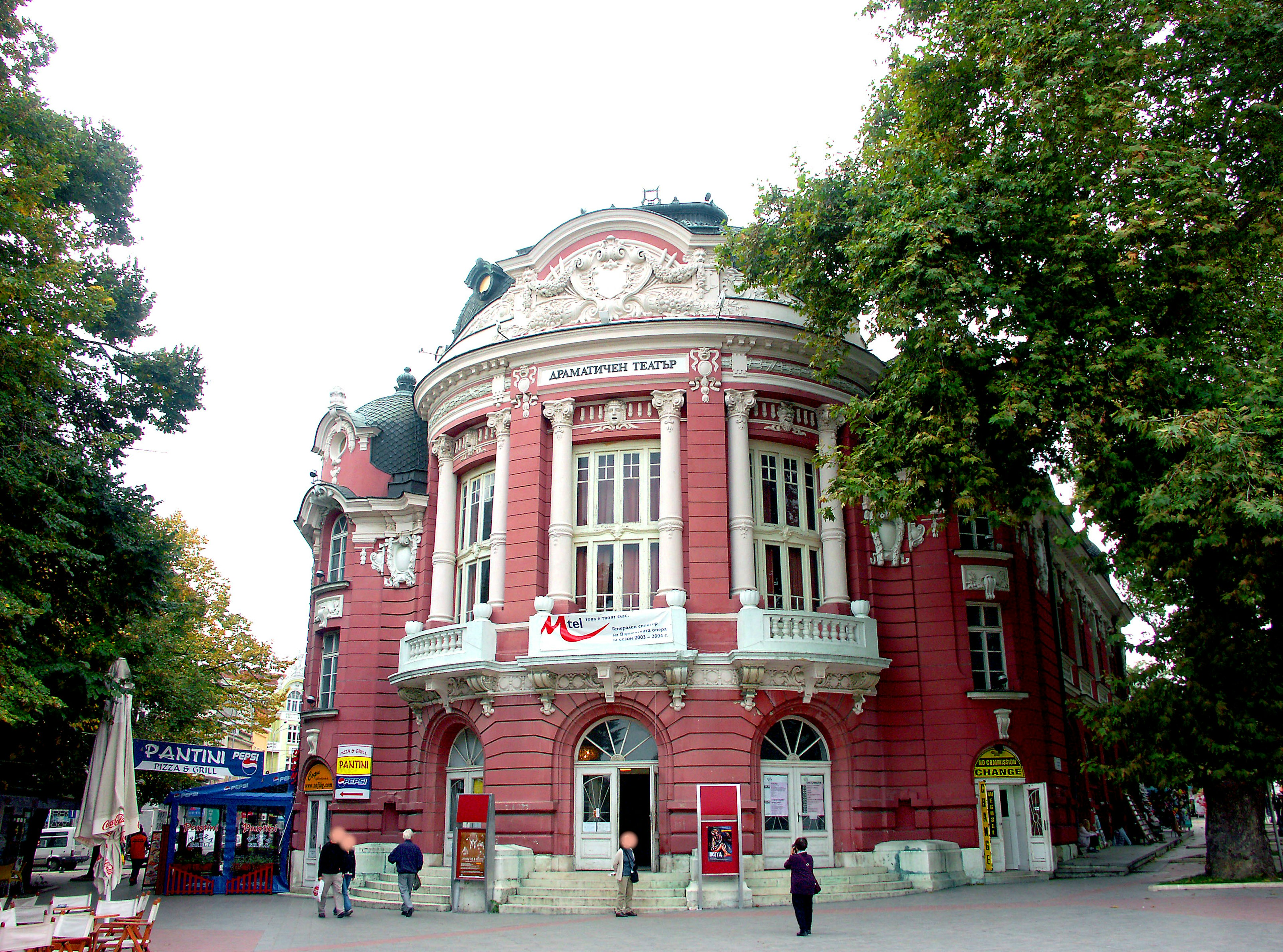 Beautiful historic building with red facade surrounded by green trees