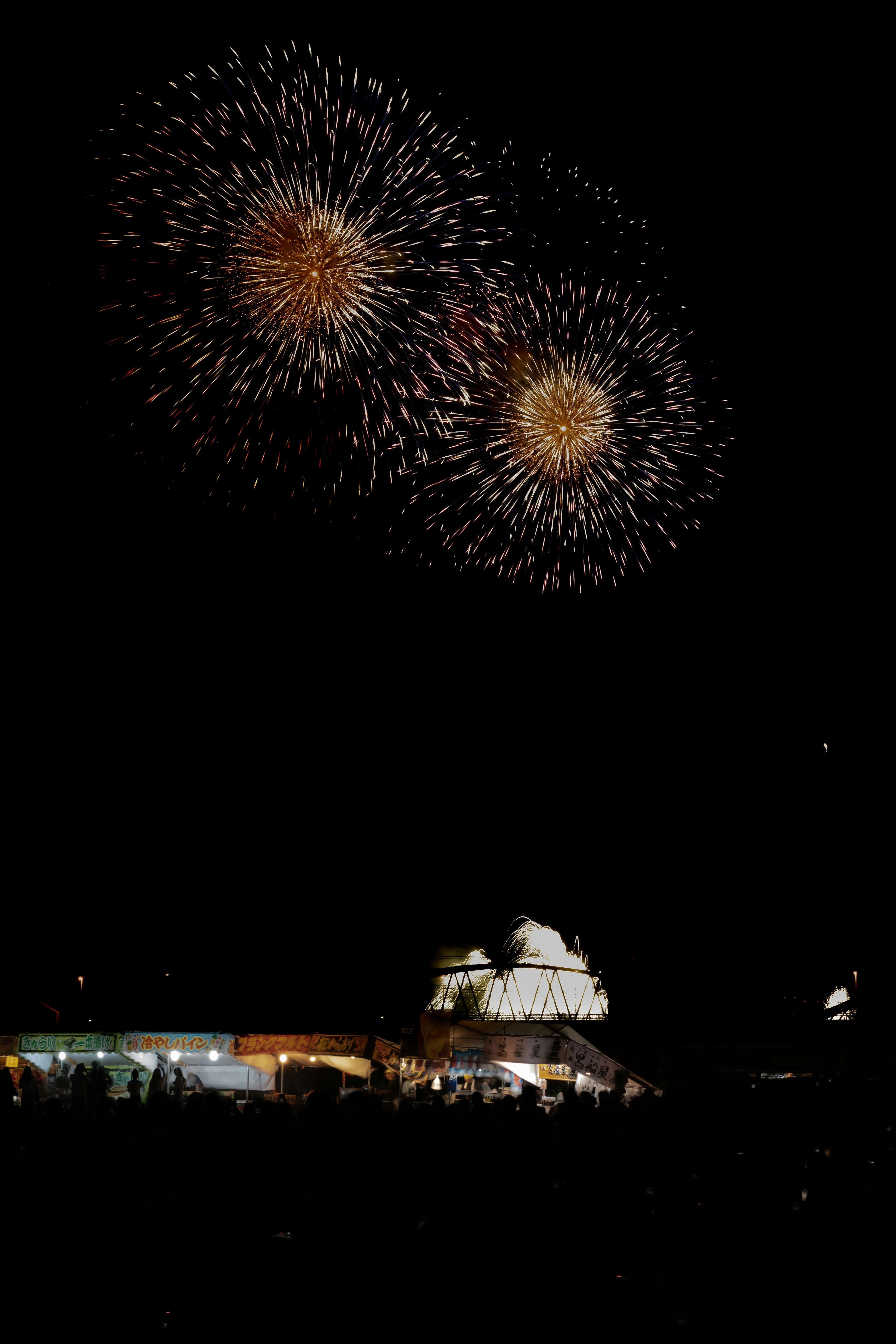 夜空に輝く花火とその下の人々のシルエット