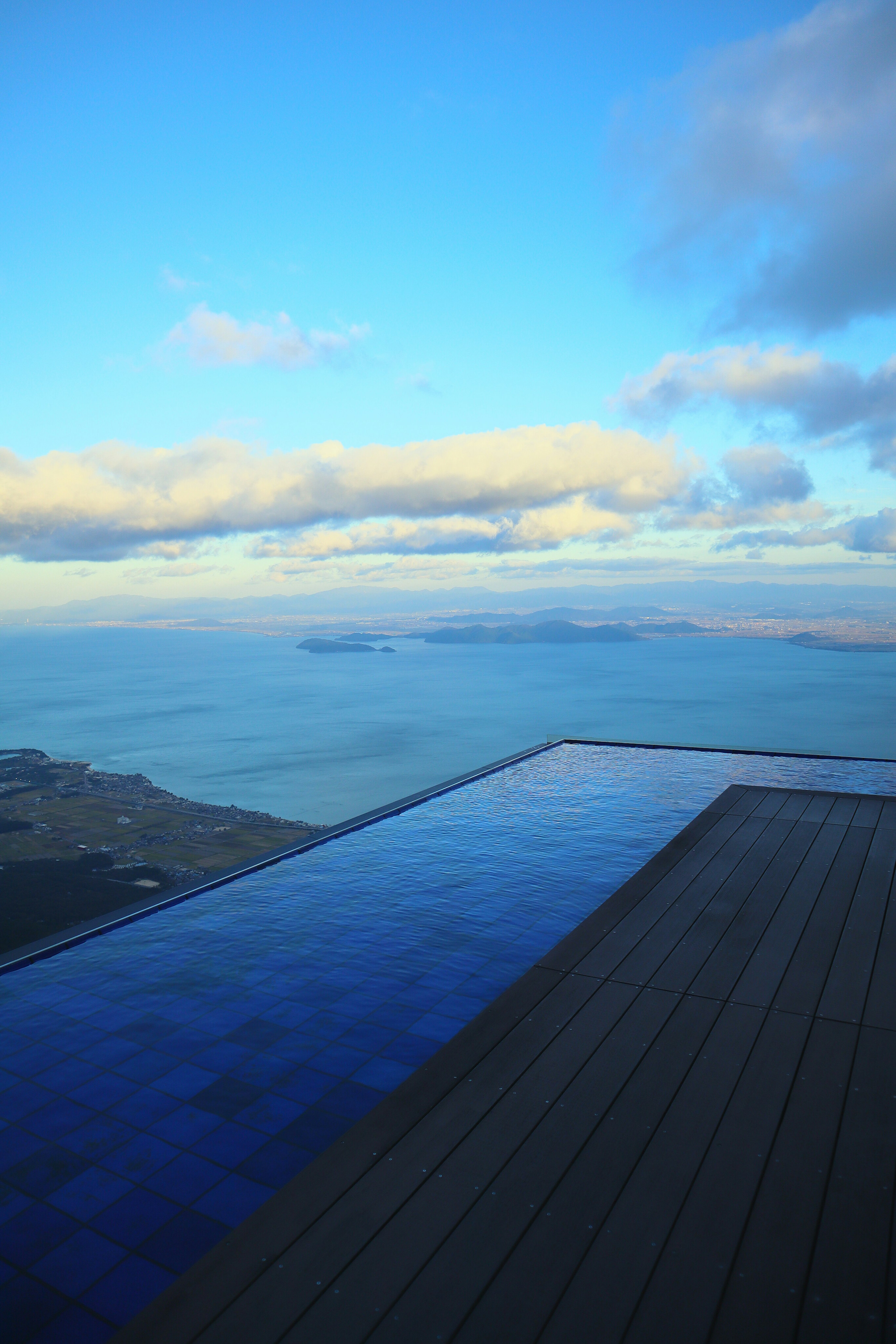 Kolam renang infinity dengan pemandangan langit biru dan pulau jauh