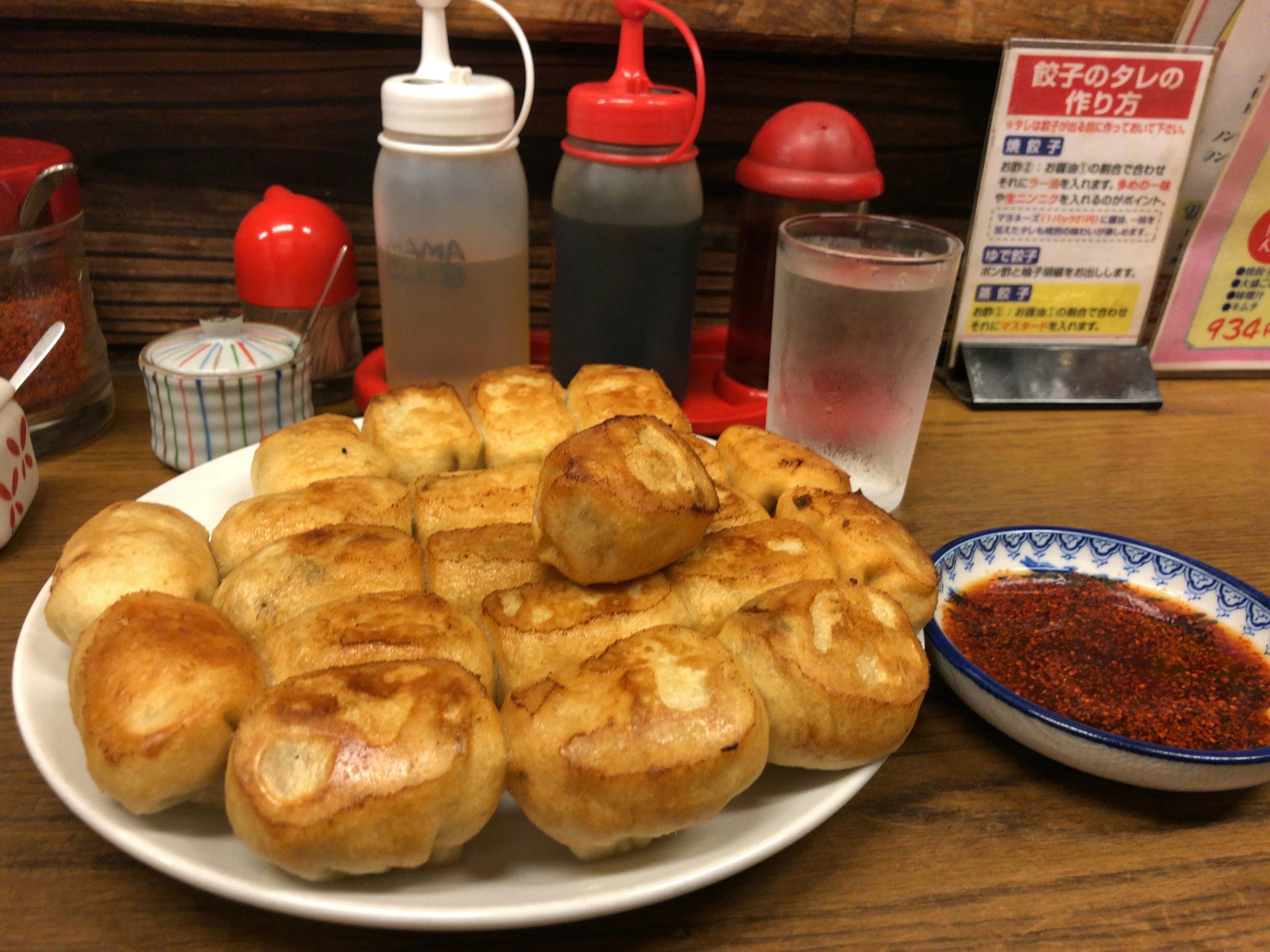 Plato de empanadillas fritas doradas con botellas de condimentos