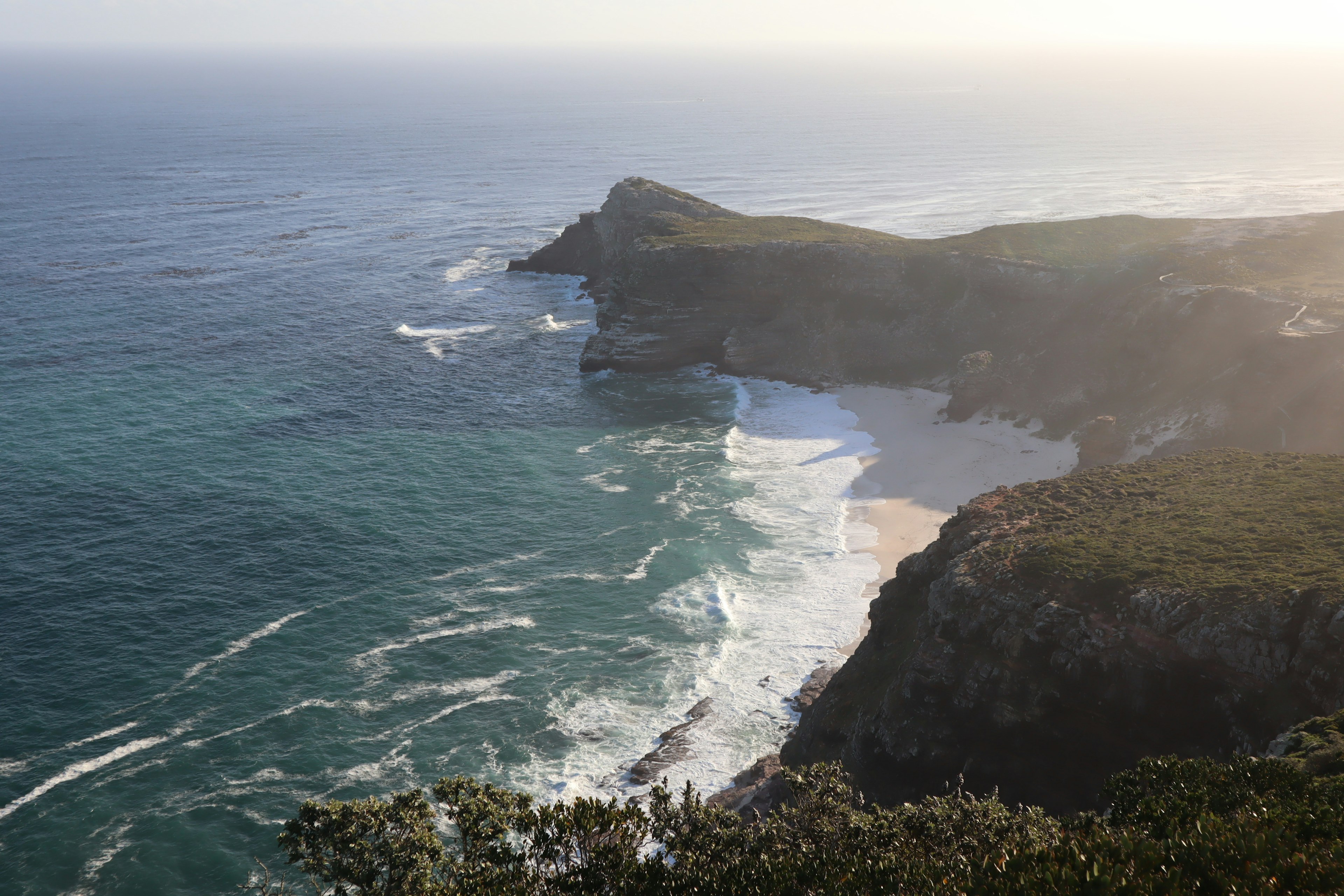 Scenic view of ocean and cliffs with sunlight shining