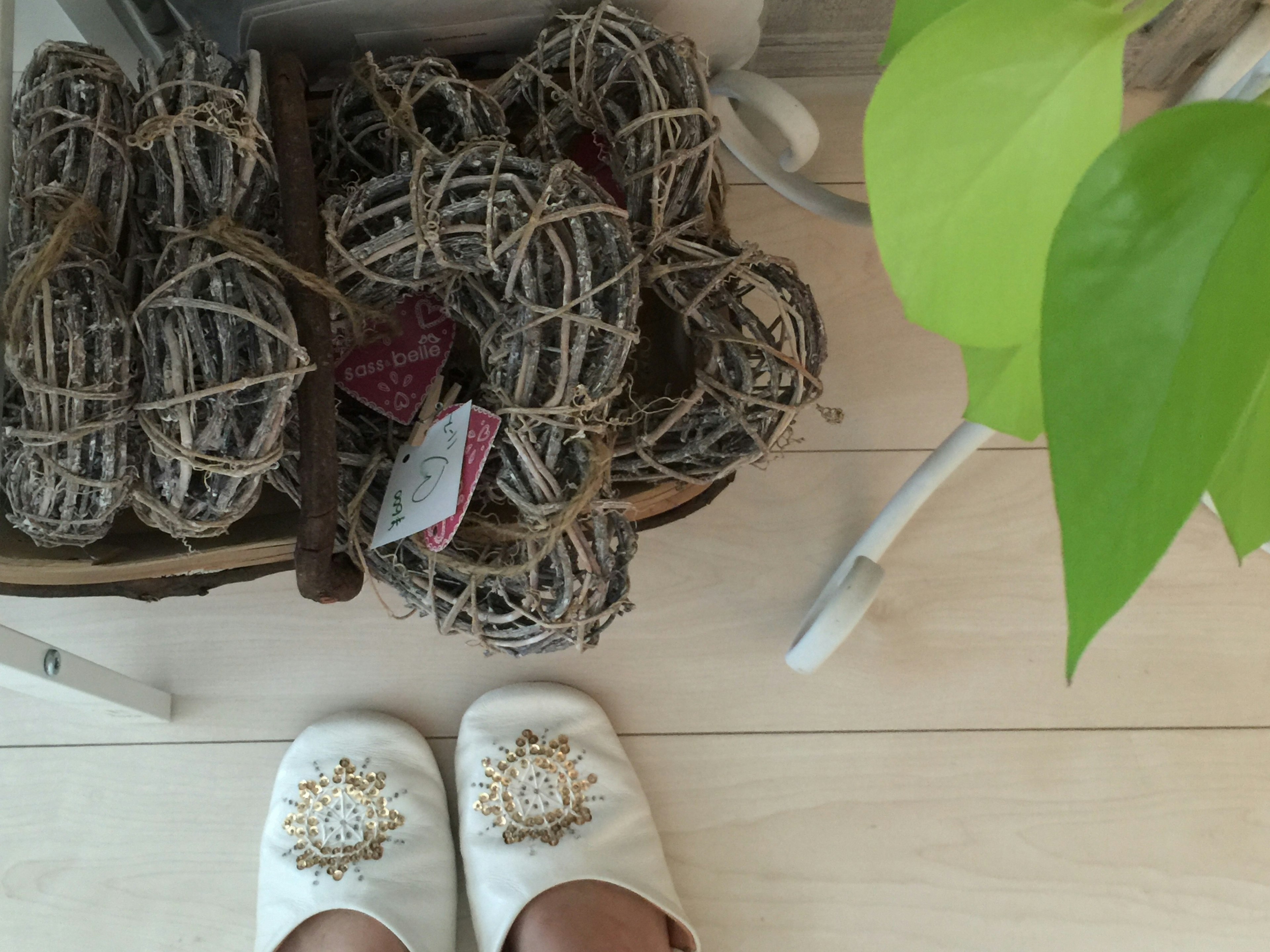 A corner of a room featuring decorative white slippers and a basket filled with wicker balls