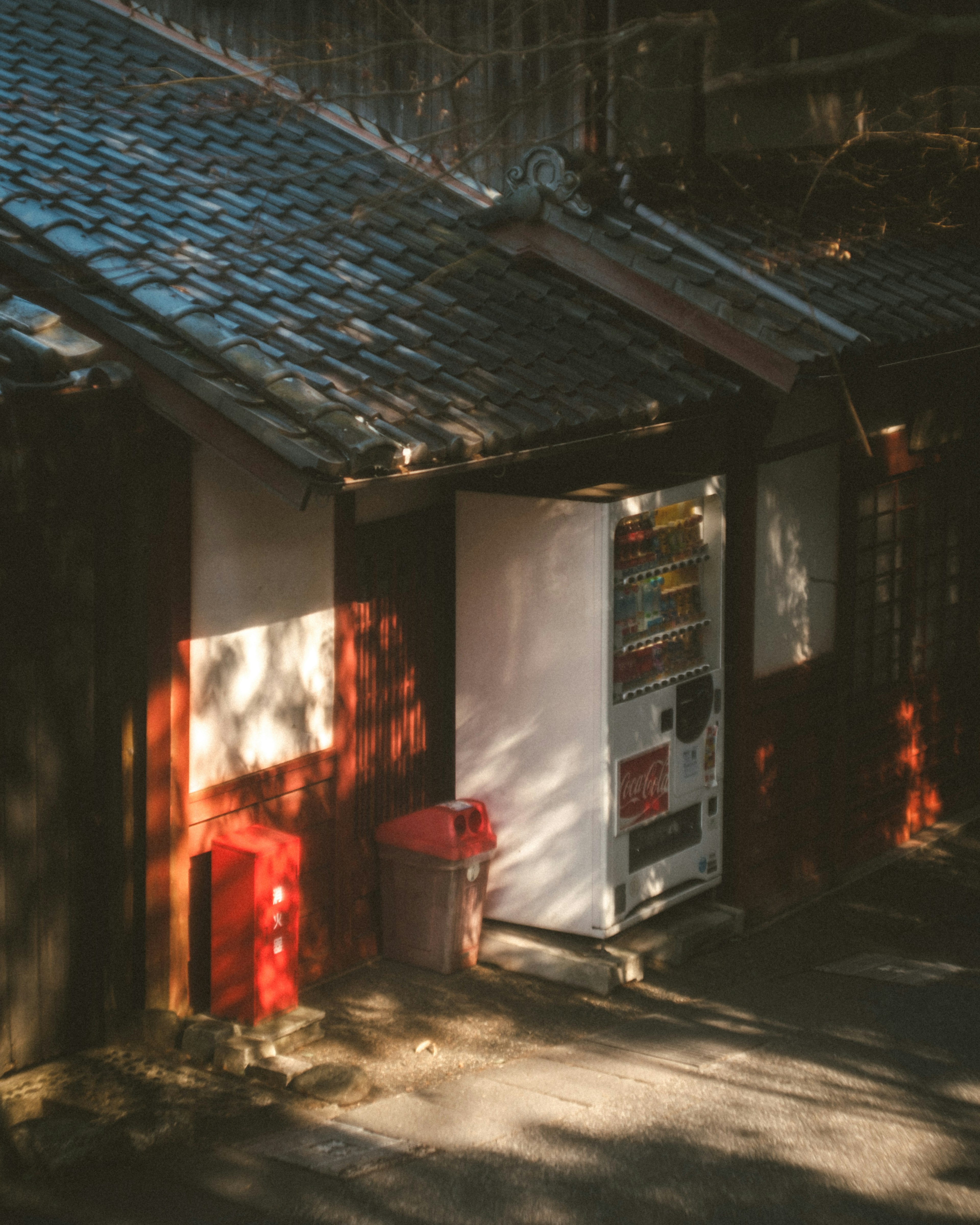 Distributeur automatique et poubelle à côté d'un vieux bâtiment avec des ombres