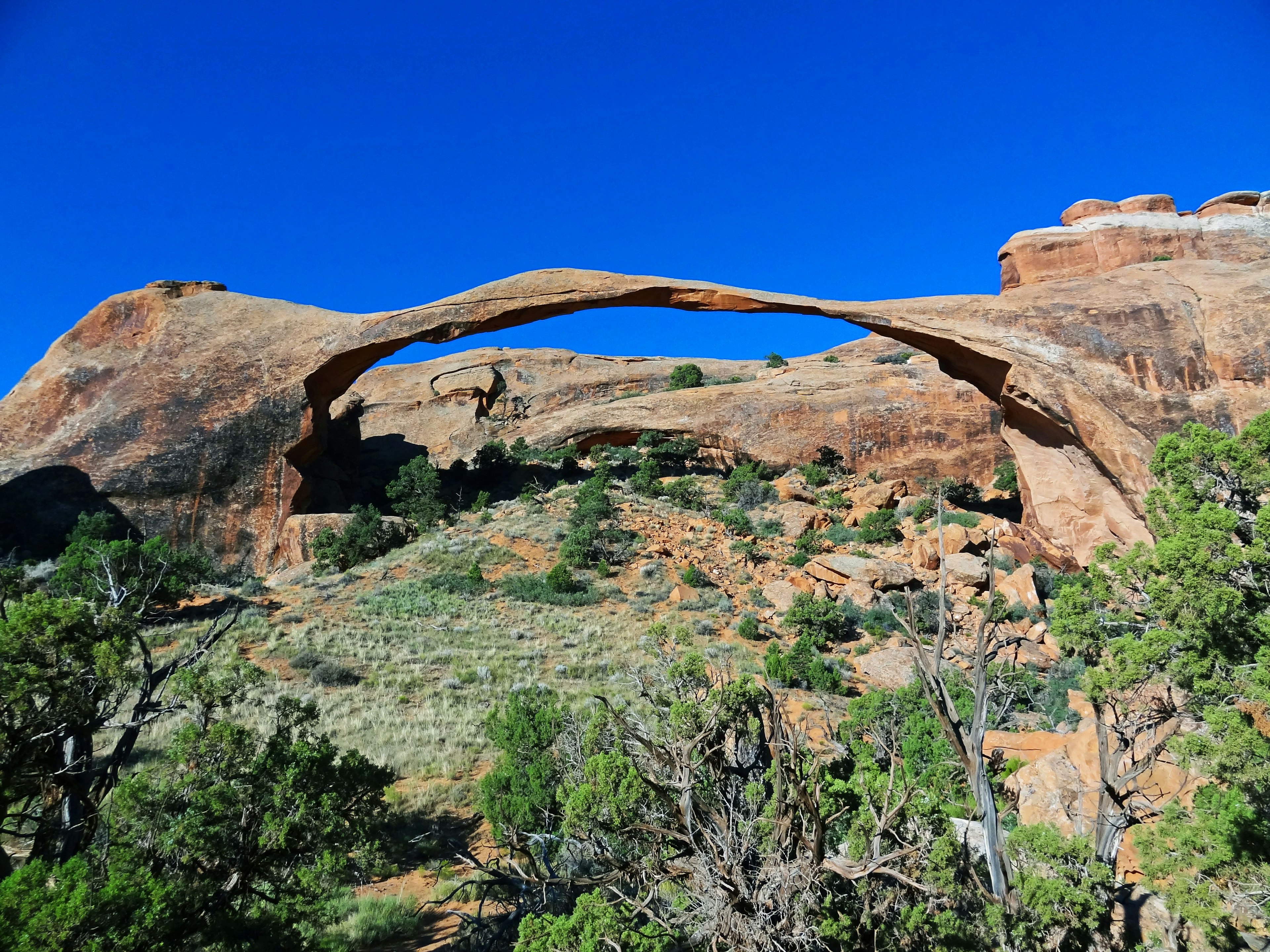 Arco de roca natural con cielo azul y vegetación verde