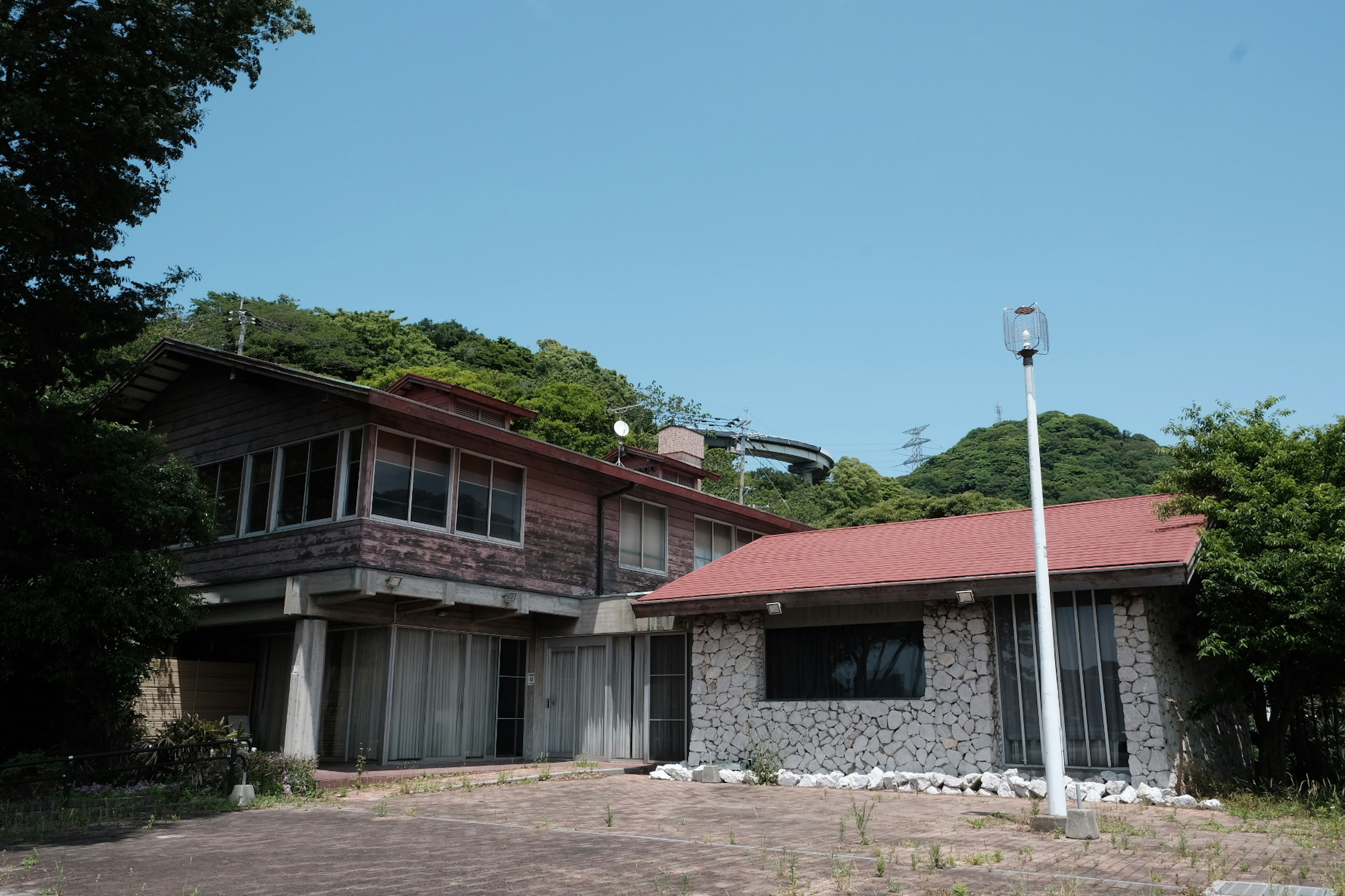 Rumah dua lantai dengan atap merah dan bangunan satu lantai berdampingan