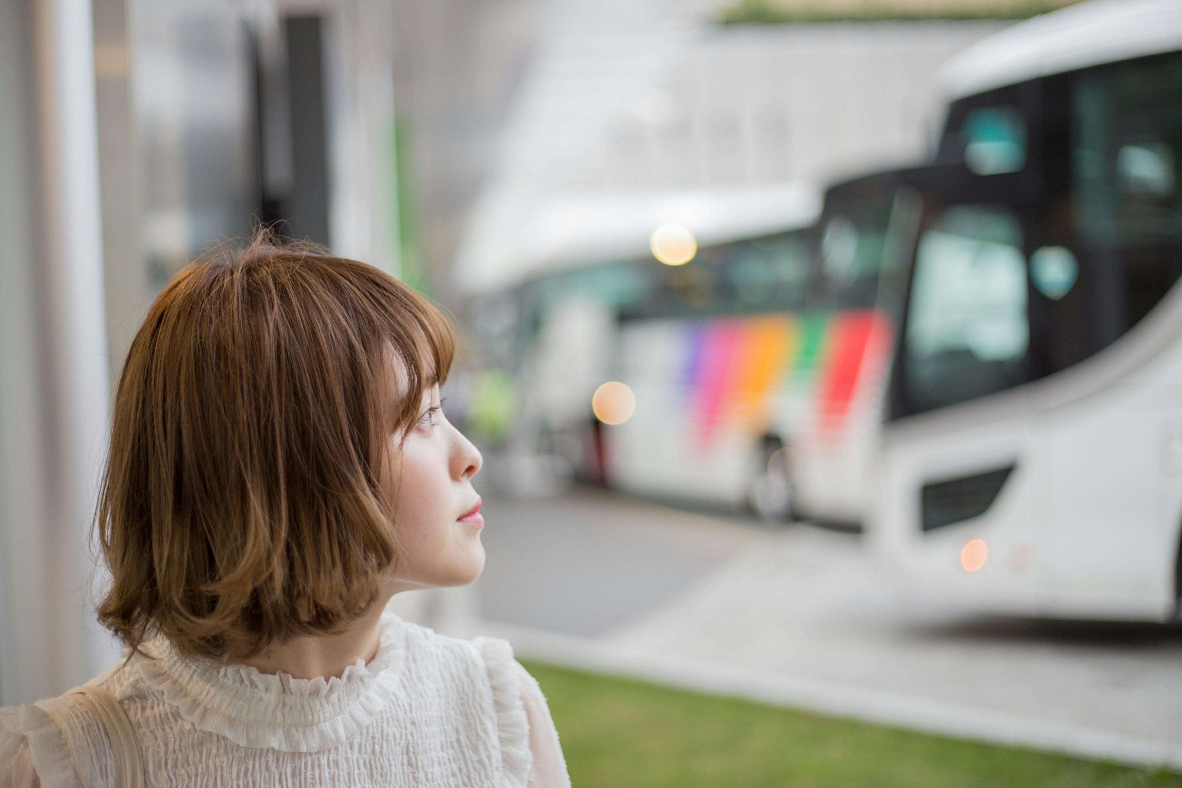 Una mujer mirando un autobús Mujer de cabello corto con atuendo blanco Diseño de autobús colorido