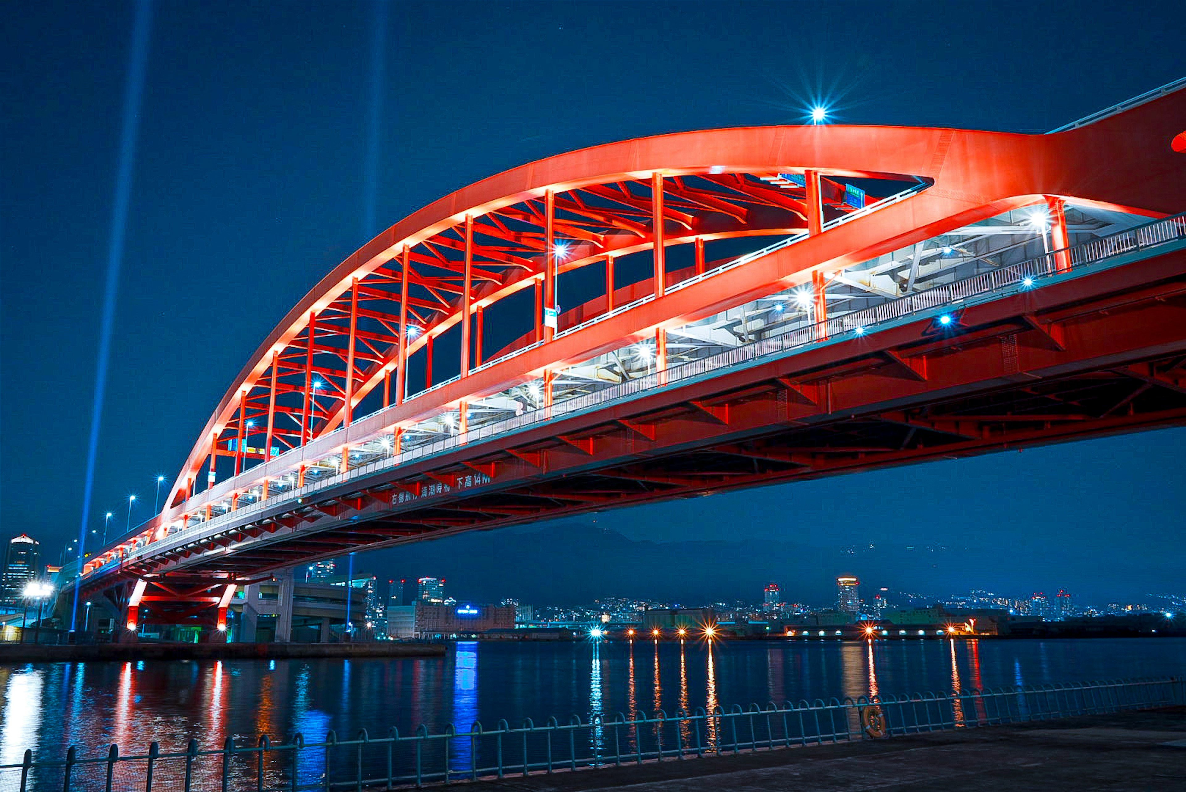 Night view of a red arch bridge with reflections in the water