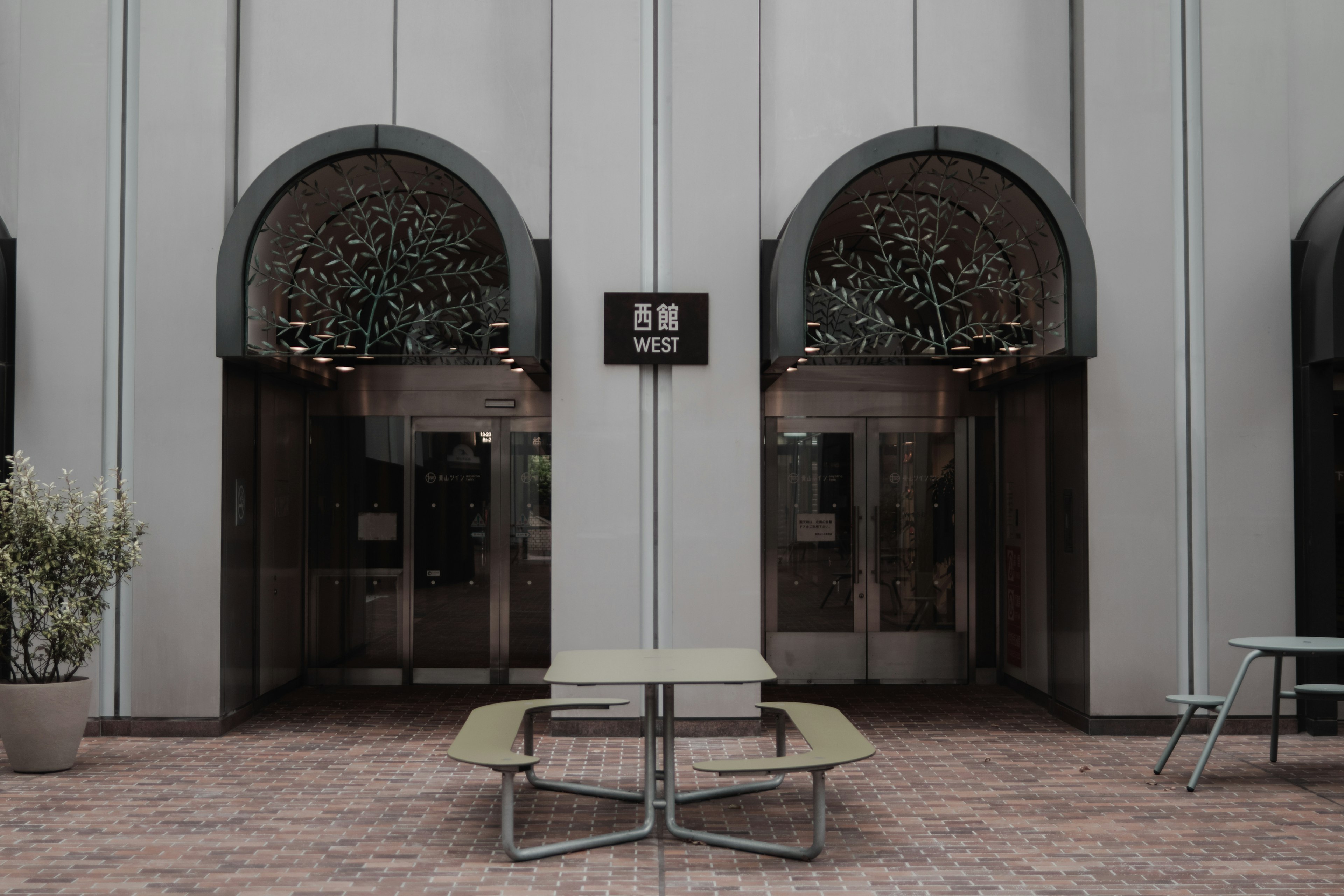 Entrance with two arch-shaped doors and a table surrounded by greenery