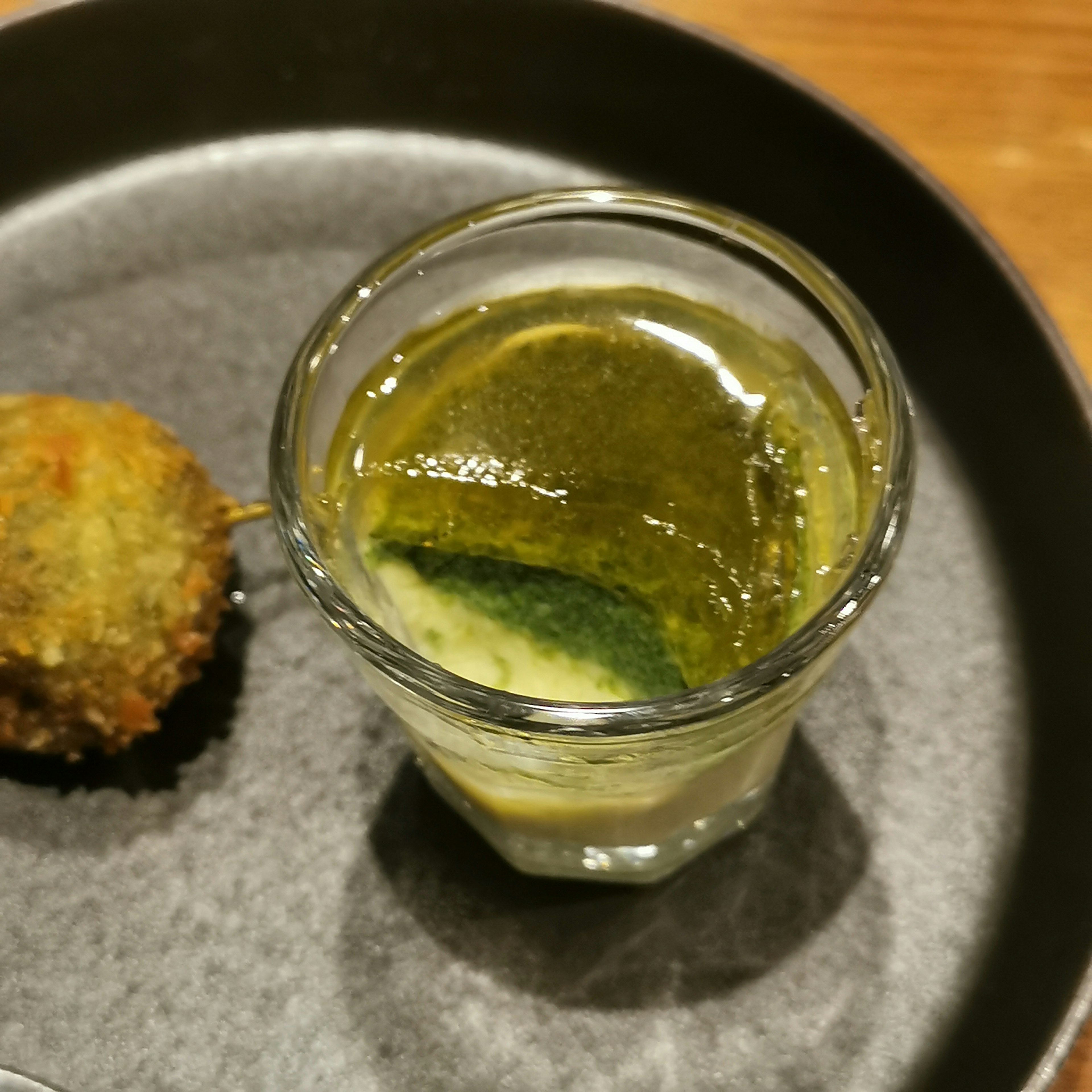 Image of a green beverage and a fried item on a black plate