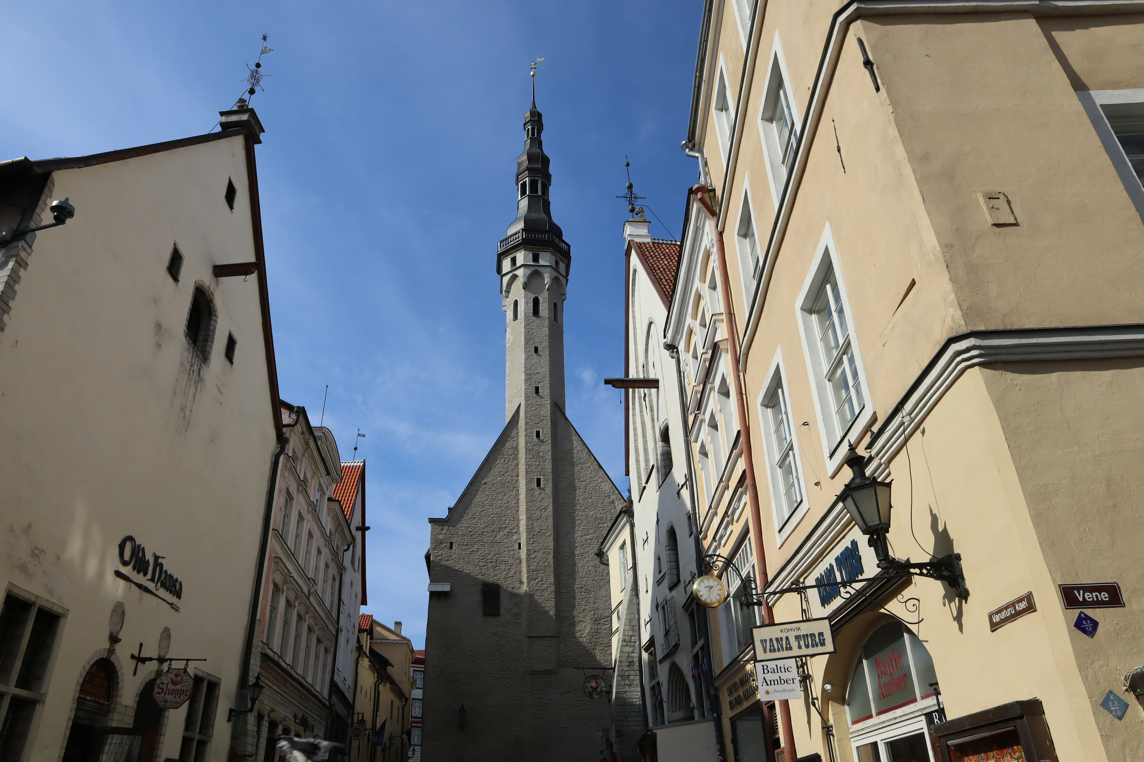 Narrow street featuring an old church tower and surrounding buildings