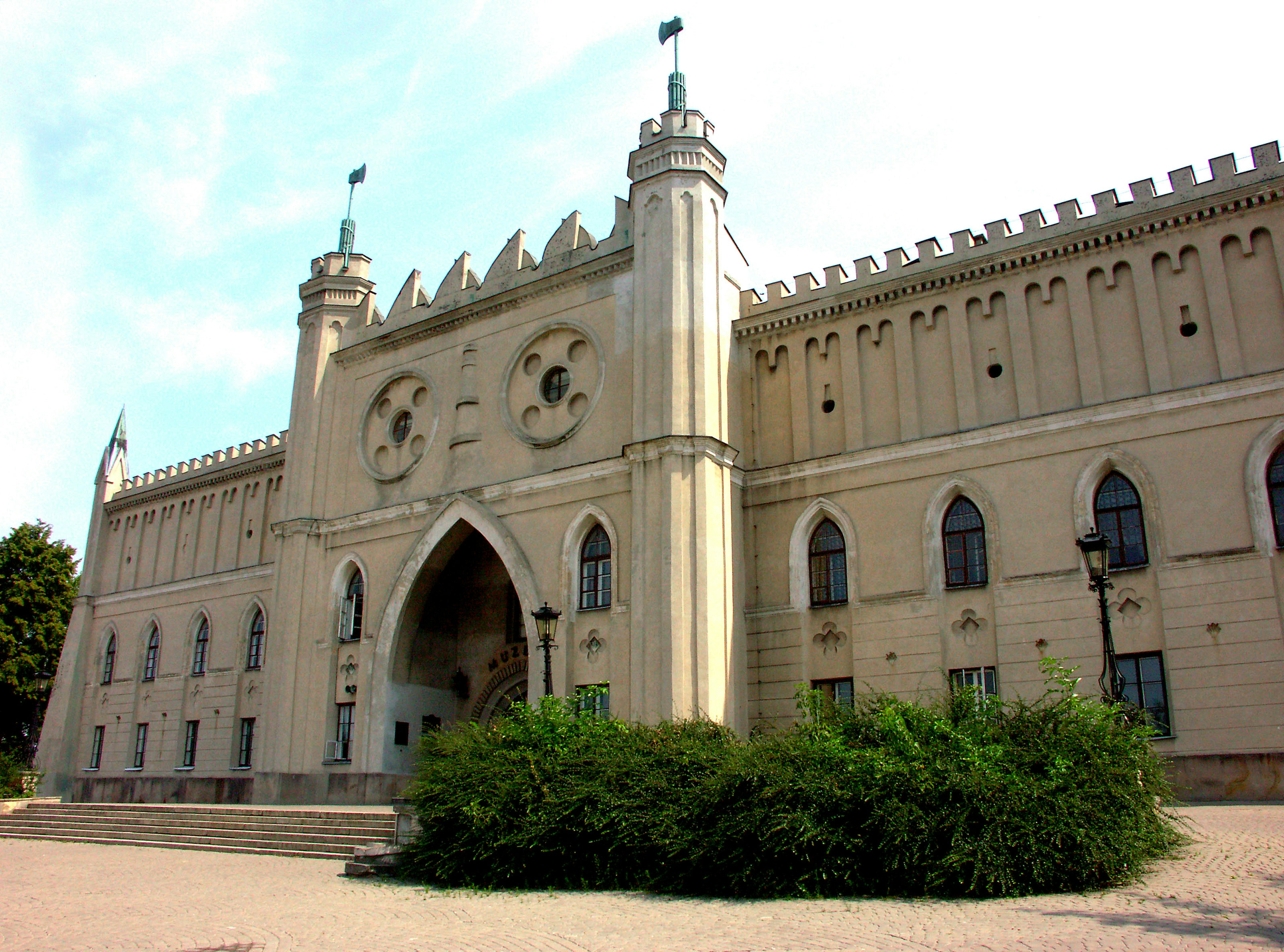 Elegante fachada de castillo de estilo gótico con vegetación en primer plano