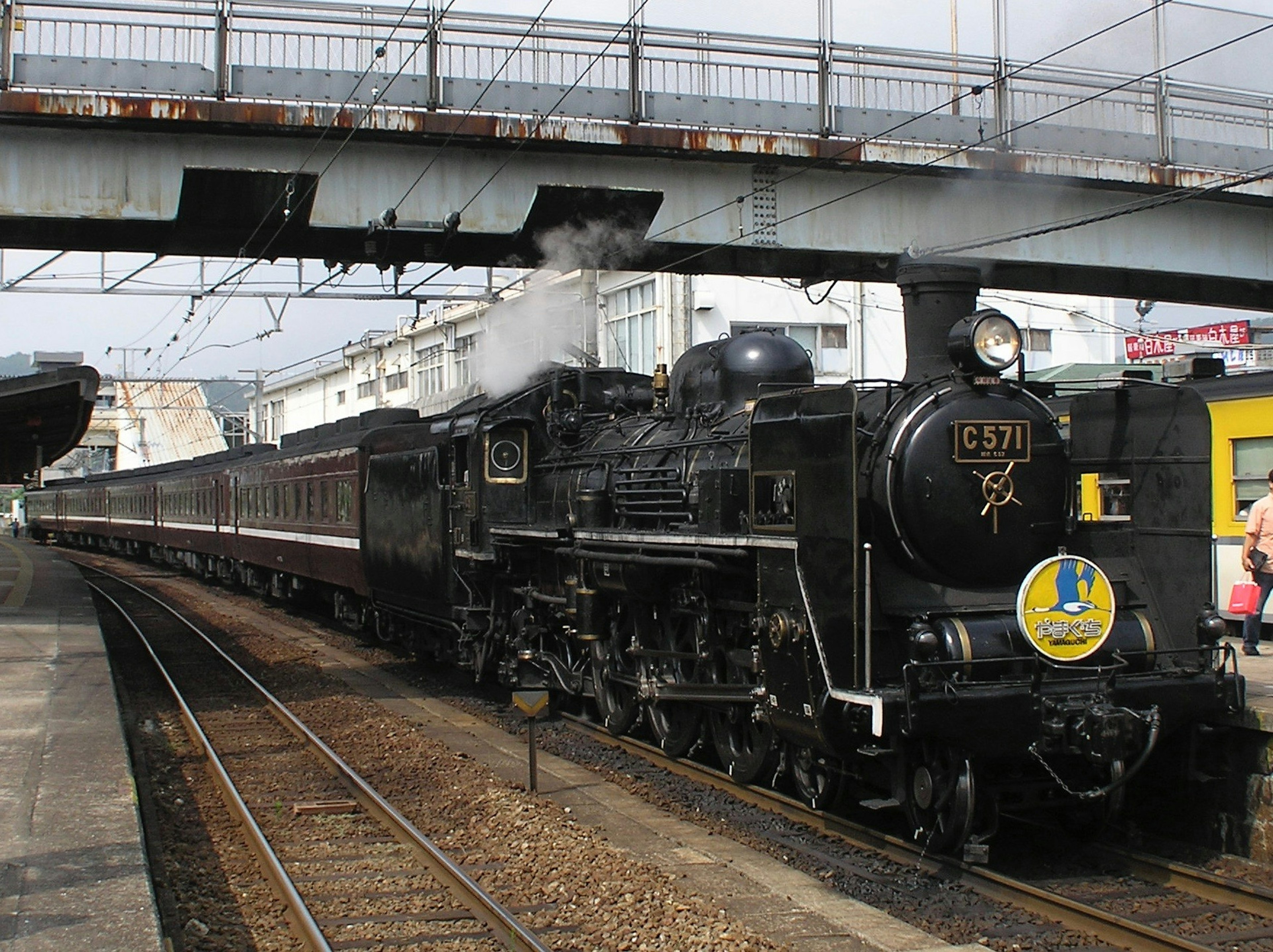 Dampflokomotive an einem Bahnhof mit angehängten historischen Wagen