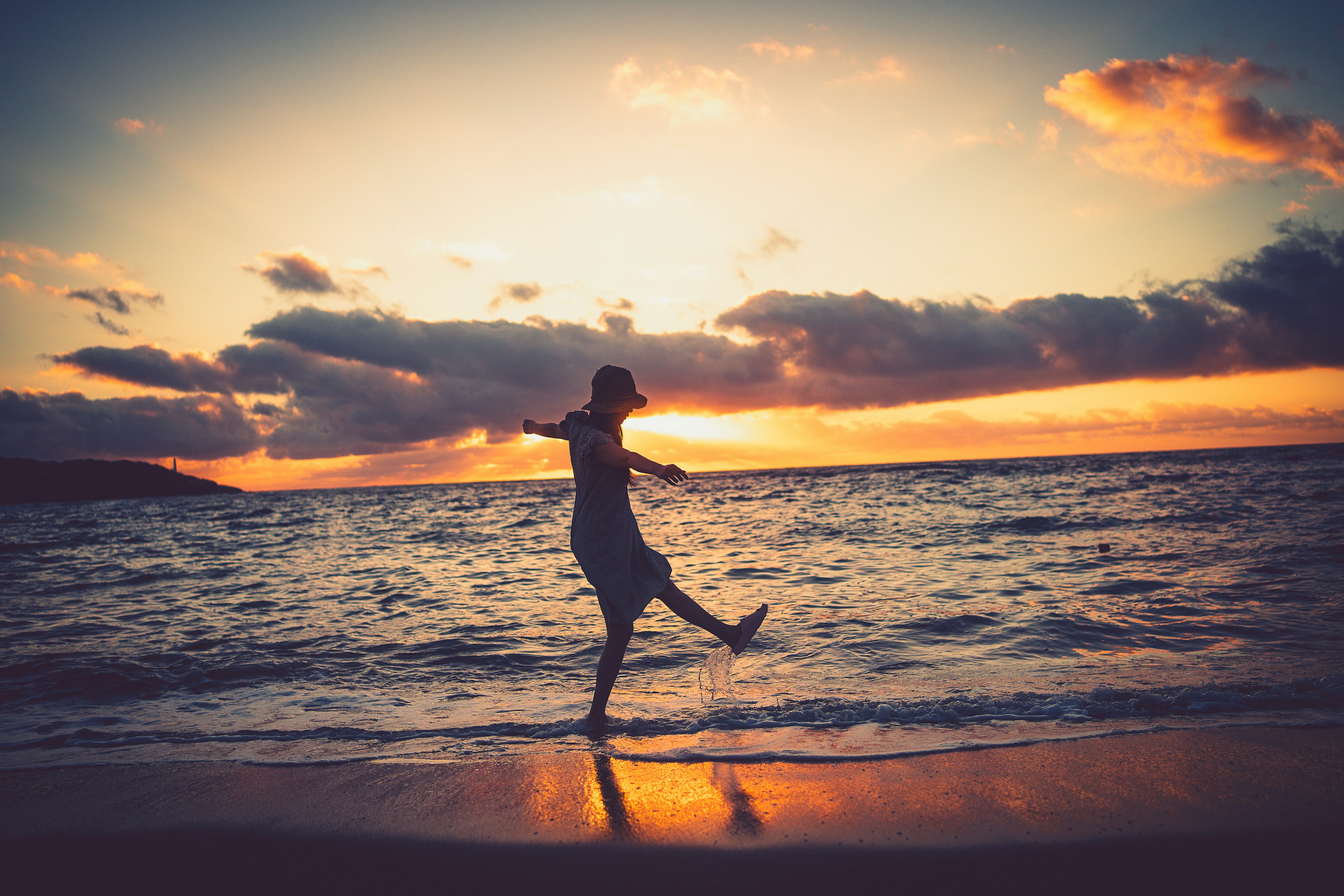 Persona che si diverte in spiaggia con il tramonto sullo sfondo