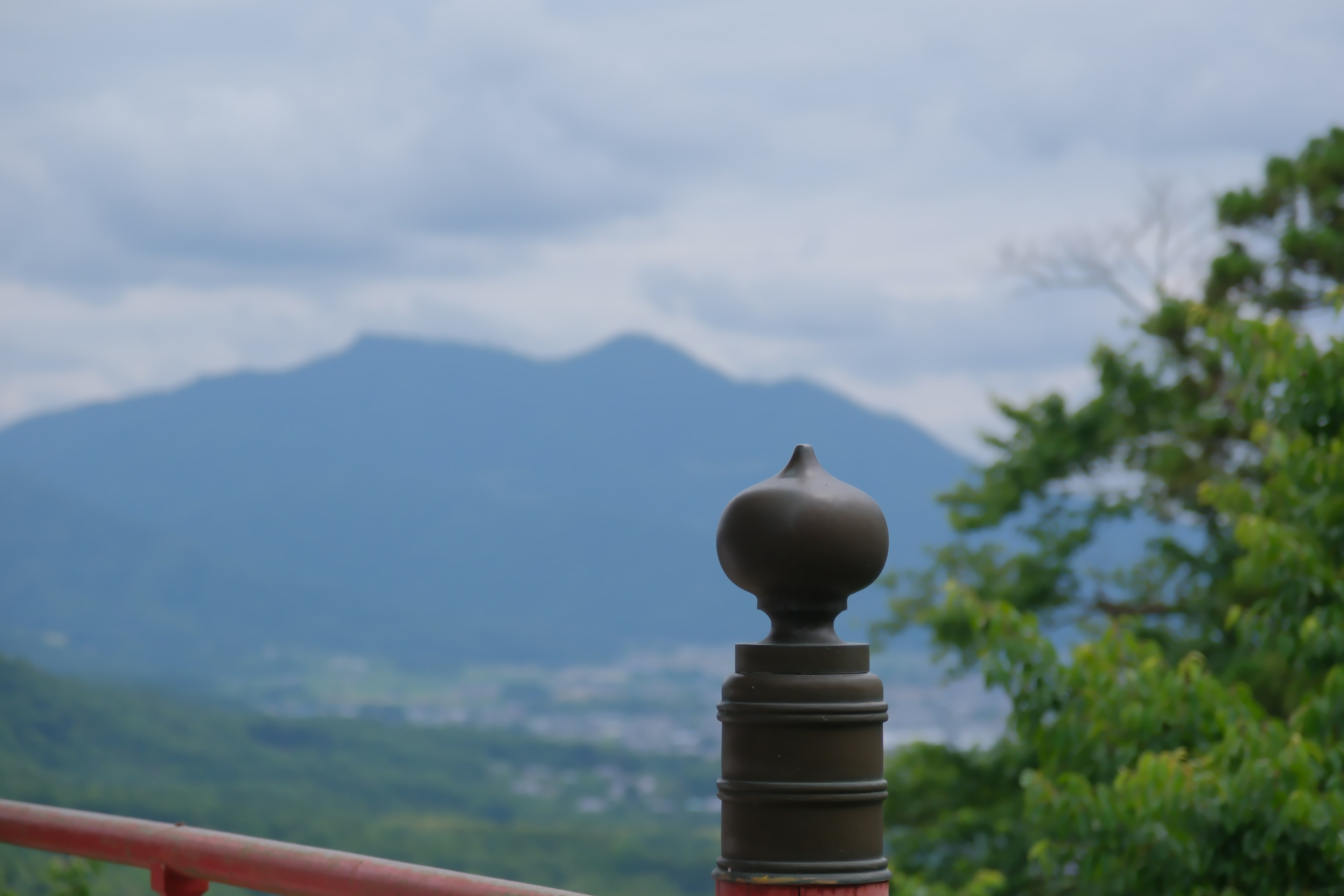 Sommità decorativa in bronzo di un pilastro con montagne sullo sfondo