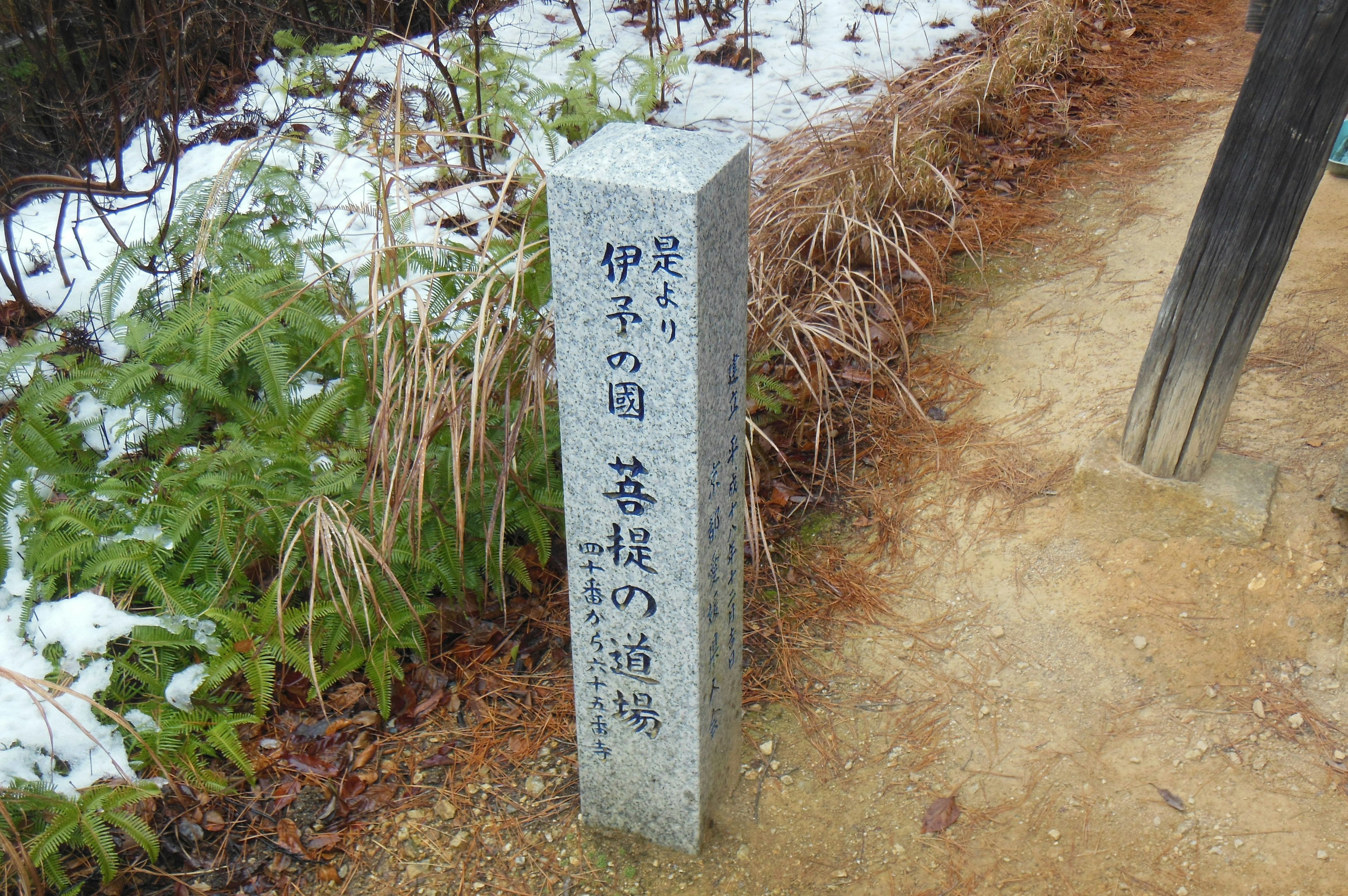 Marcador de piedra con texto japonés en un camino nevado