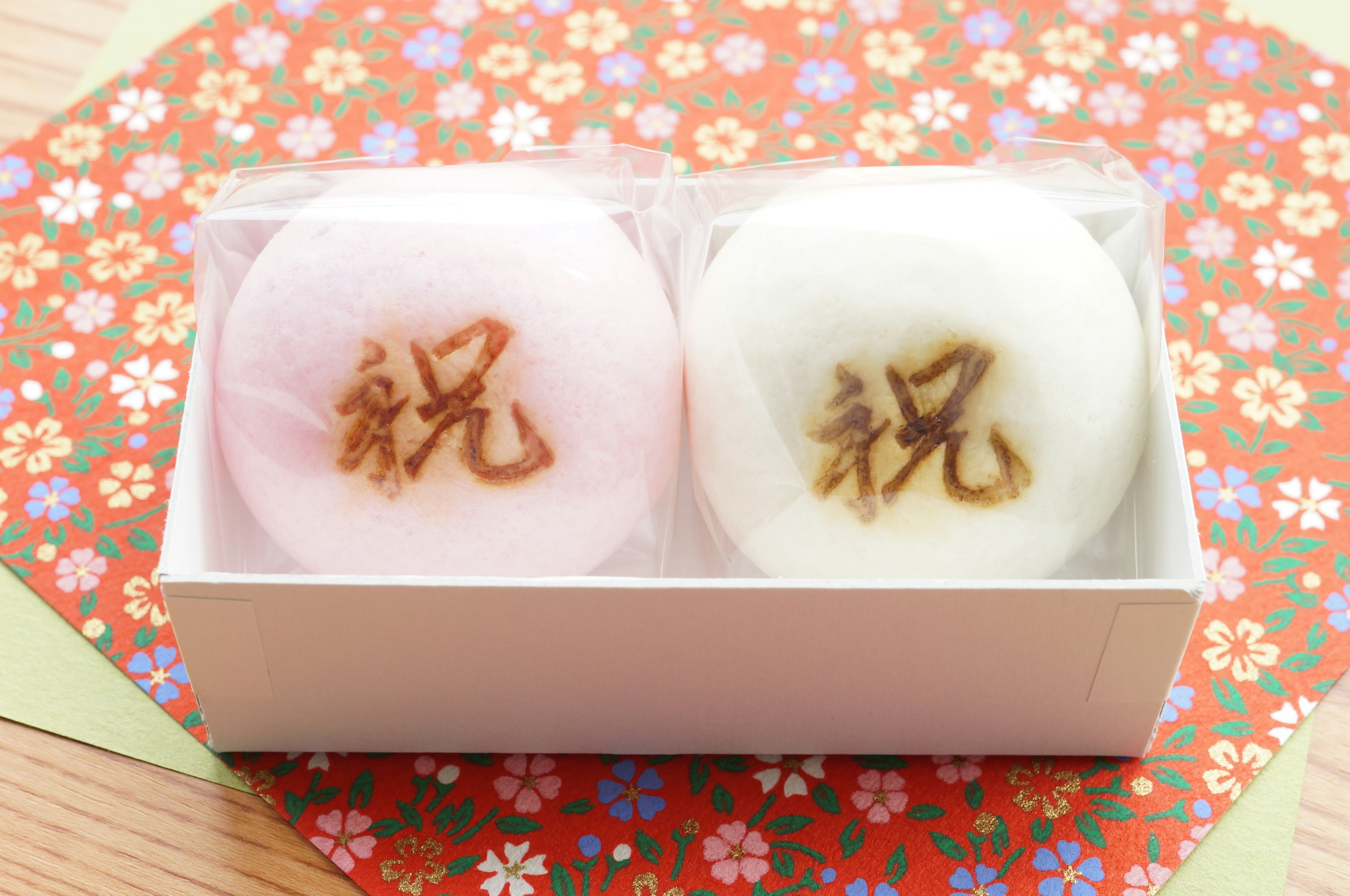 Box containing pink and white Japanese sweets with the character for celebration