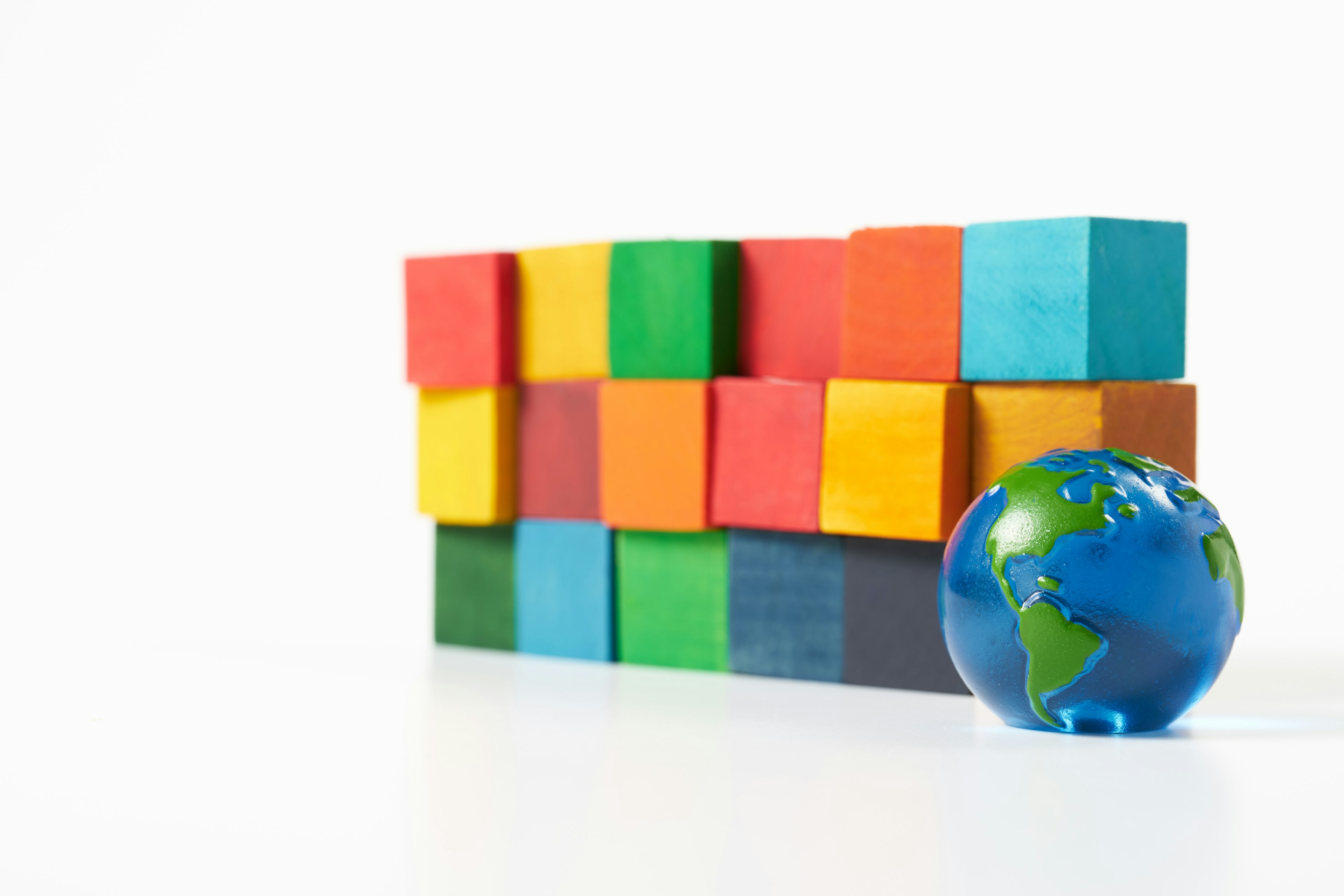 Colorful building blocks forming a wall with a globe nearby