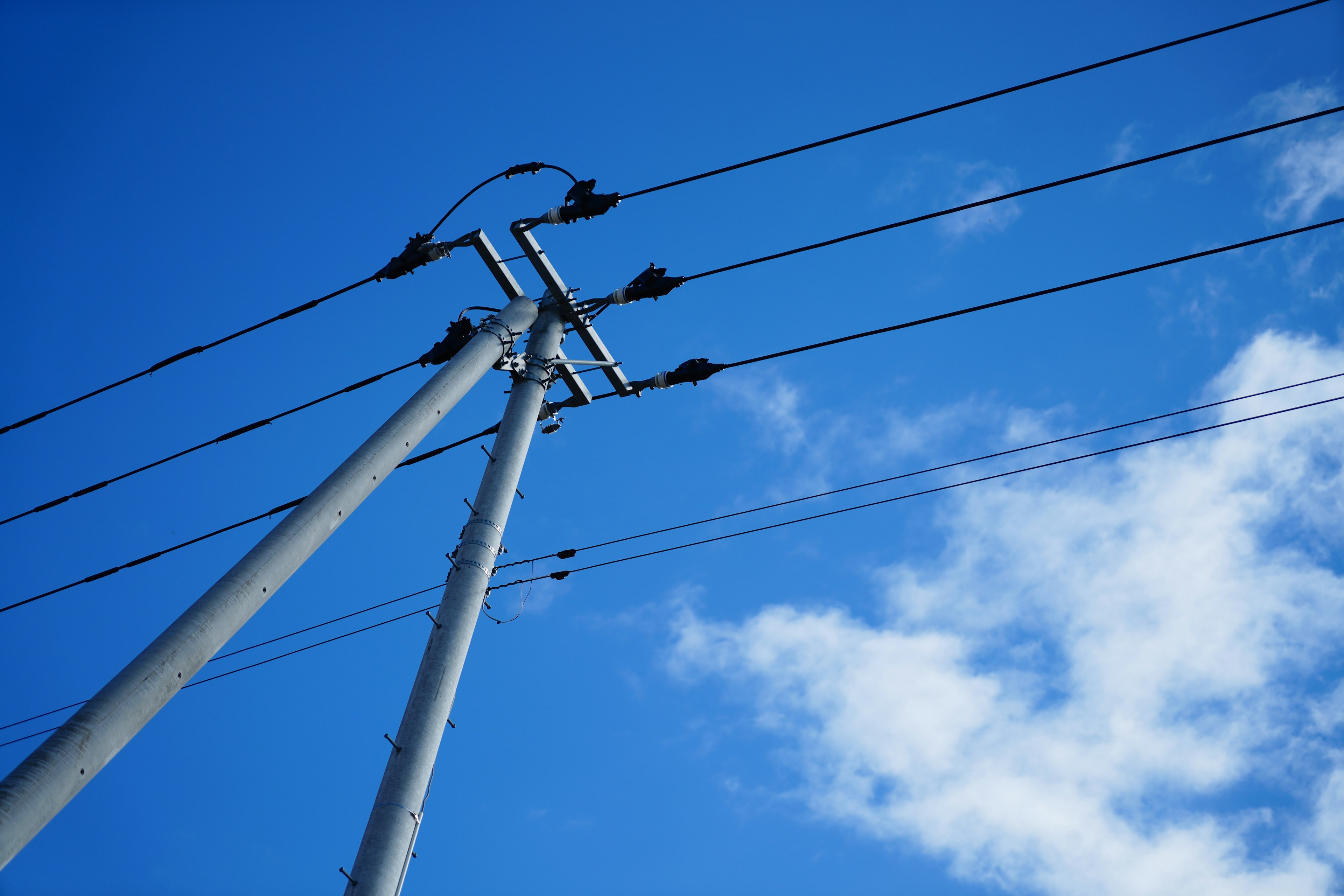 Vista de postes de luz y cables contra un cielo azul