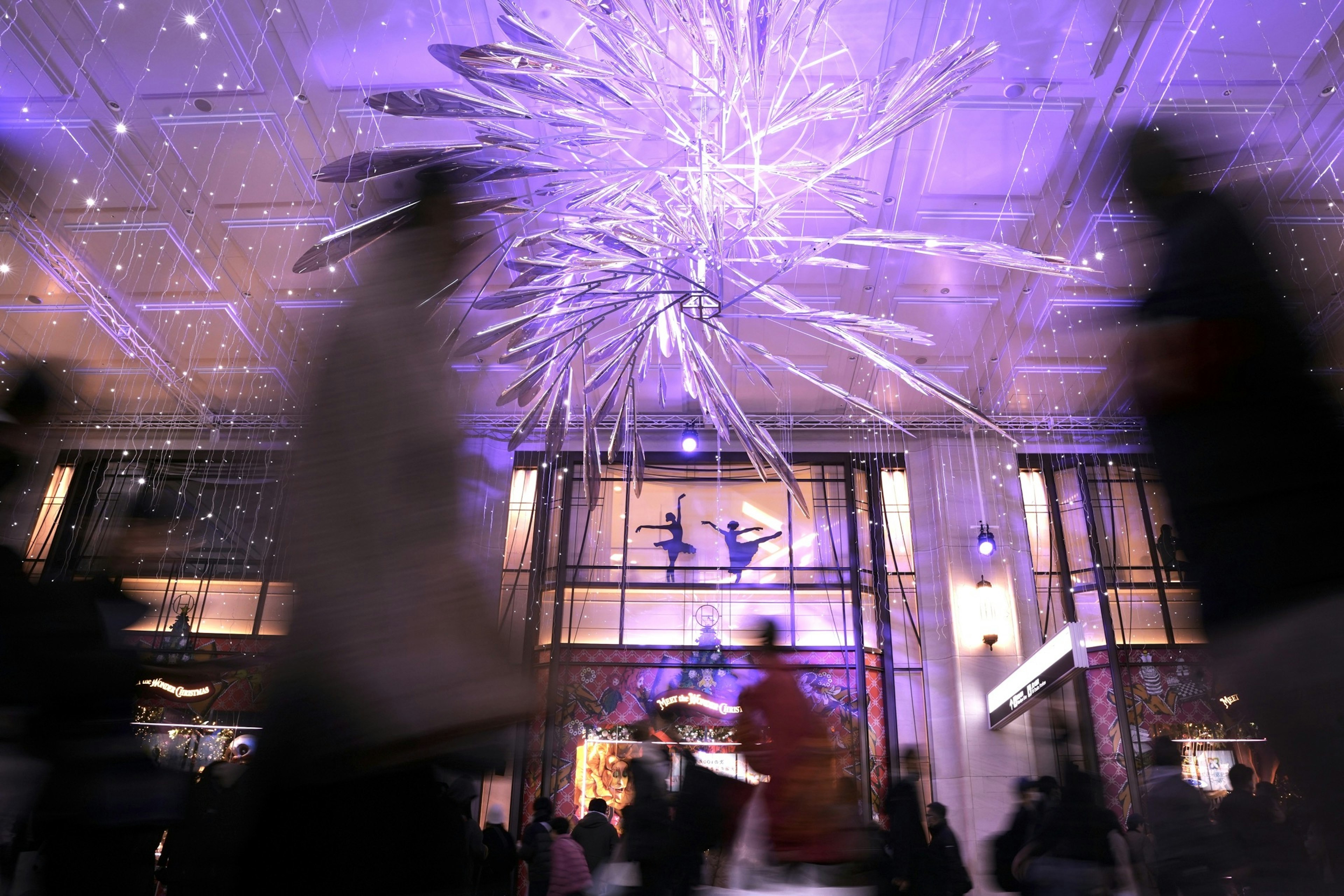 Siluetas borrosas de personas contra un fondo de luces moradas y exhibiciones decorativas