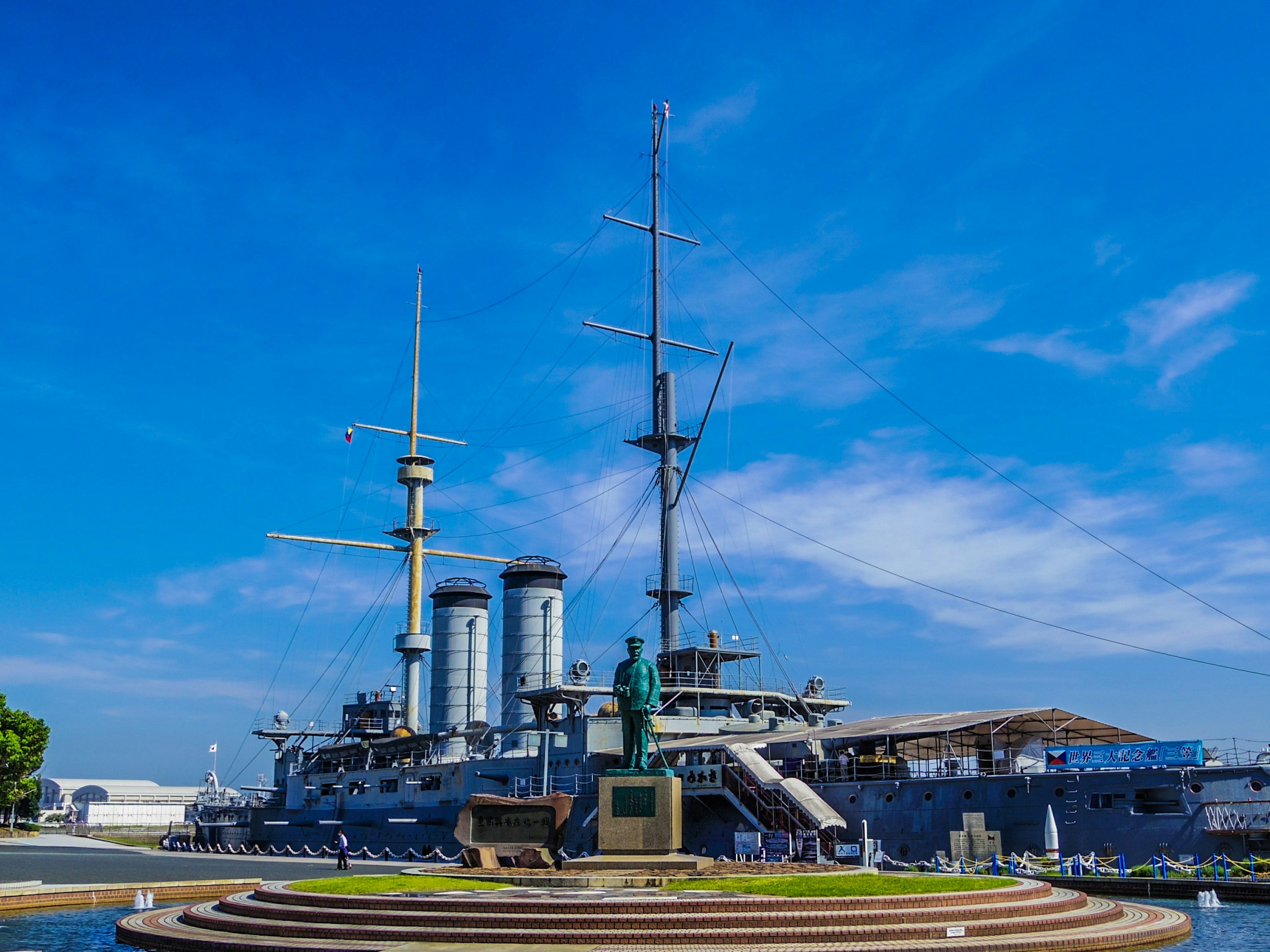 Kapal perang di bawah langit biru dengan monumen di sekitarnya