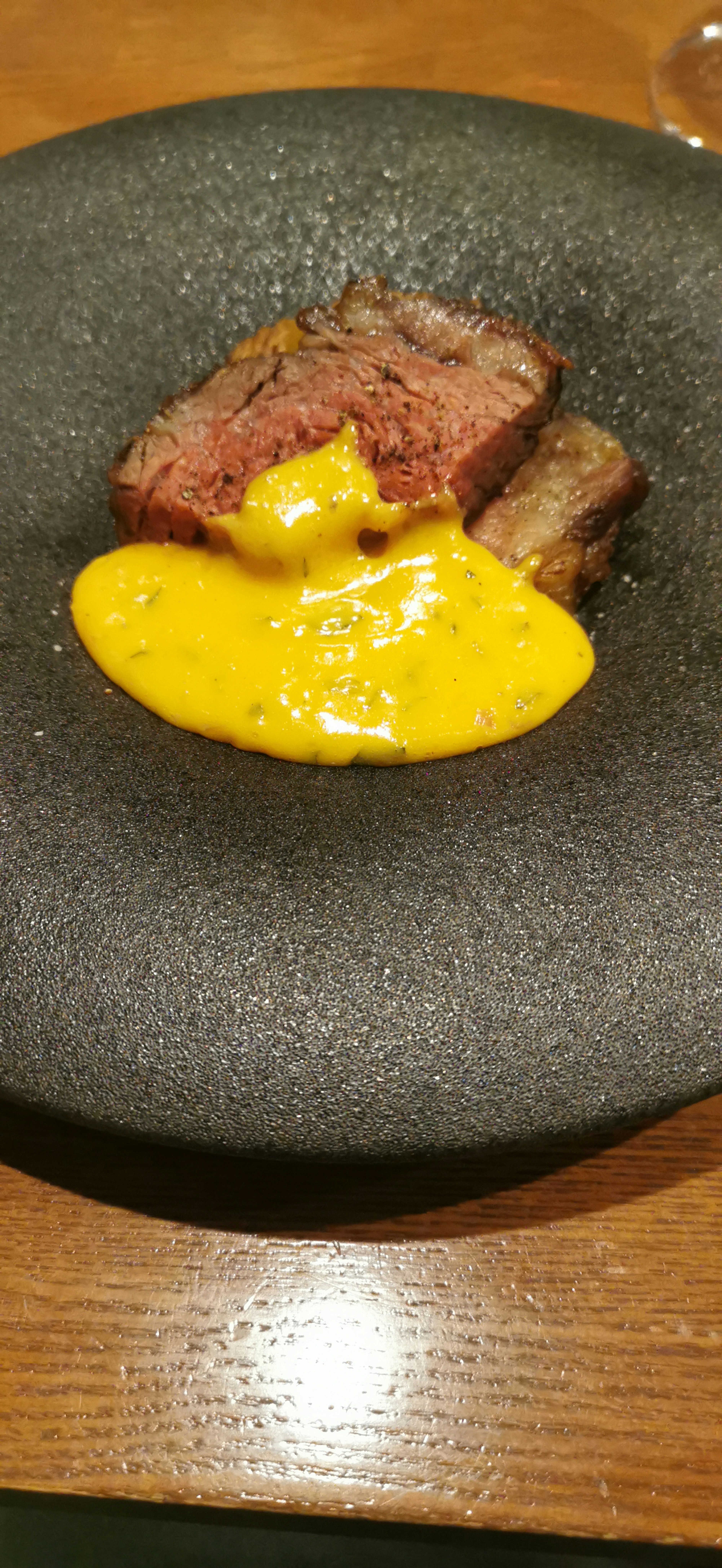 Thick cut of beef with creamy sauce on a black plate