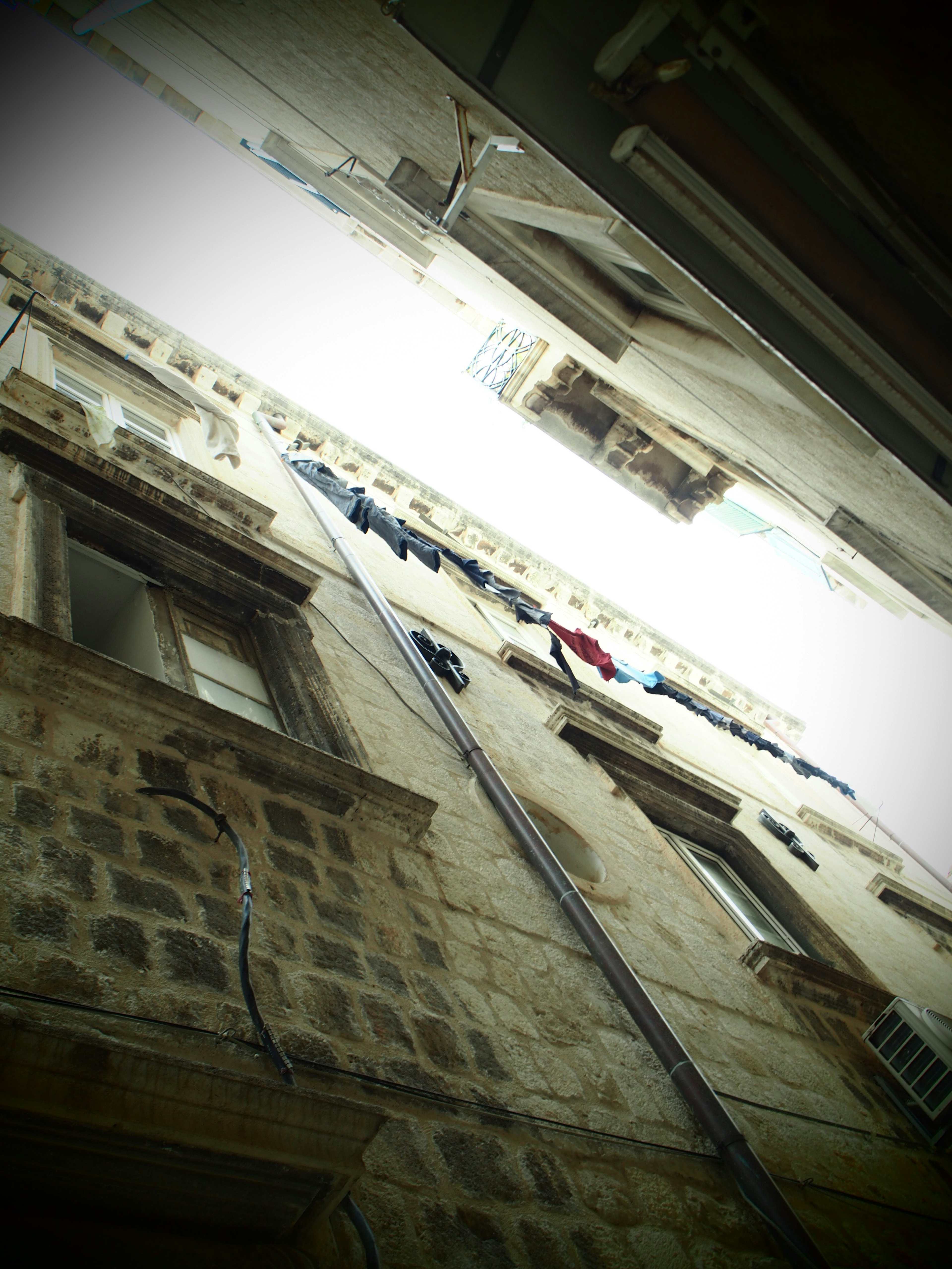 Narrow alleyway with towering old buildings laundry hanging outside