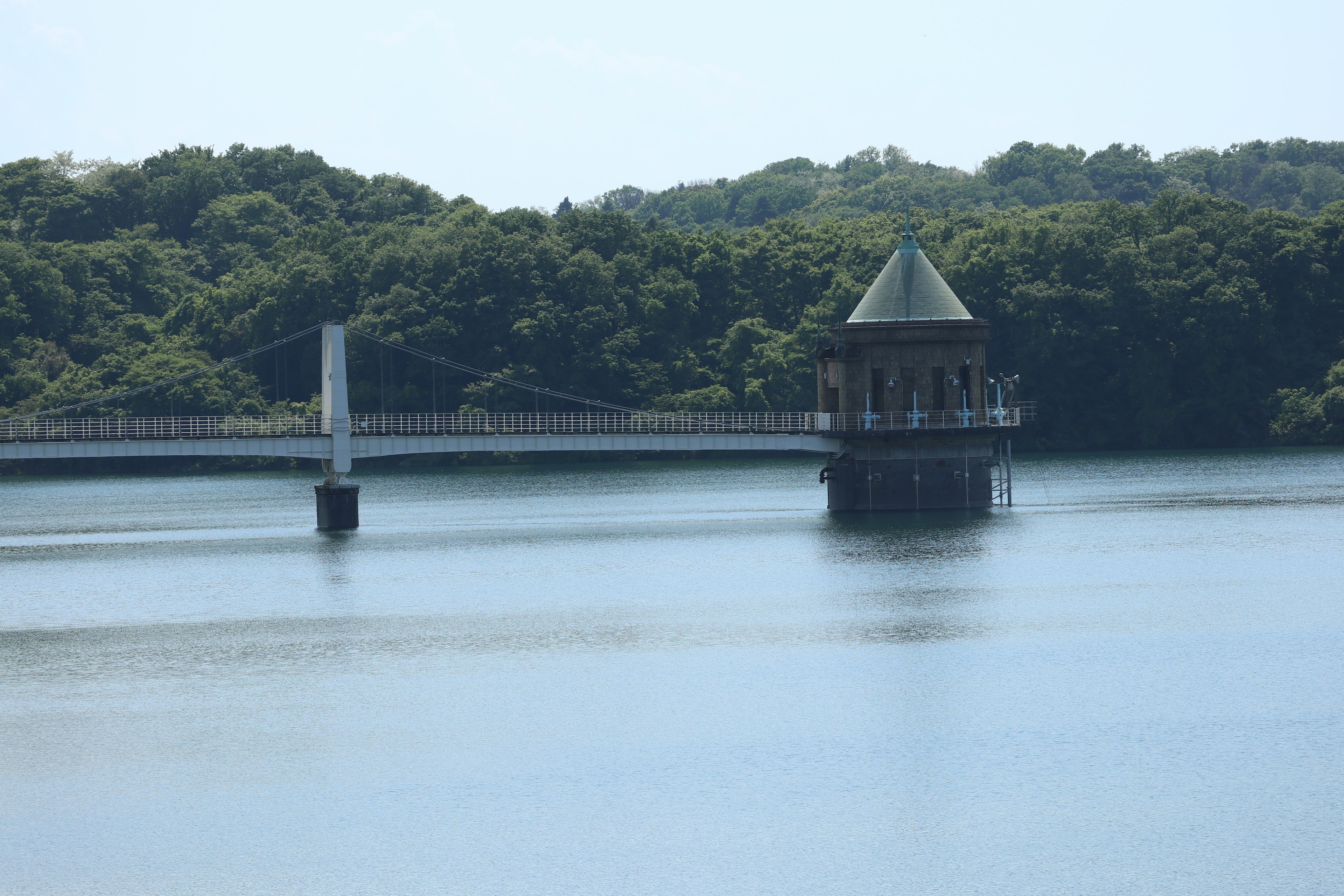 A small pavilion on the water surrounded by green forest