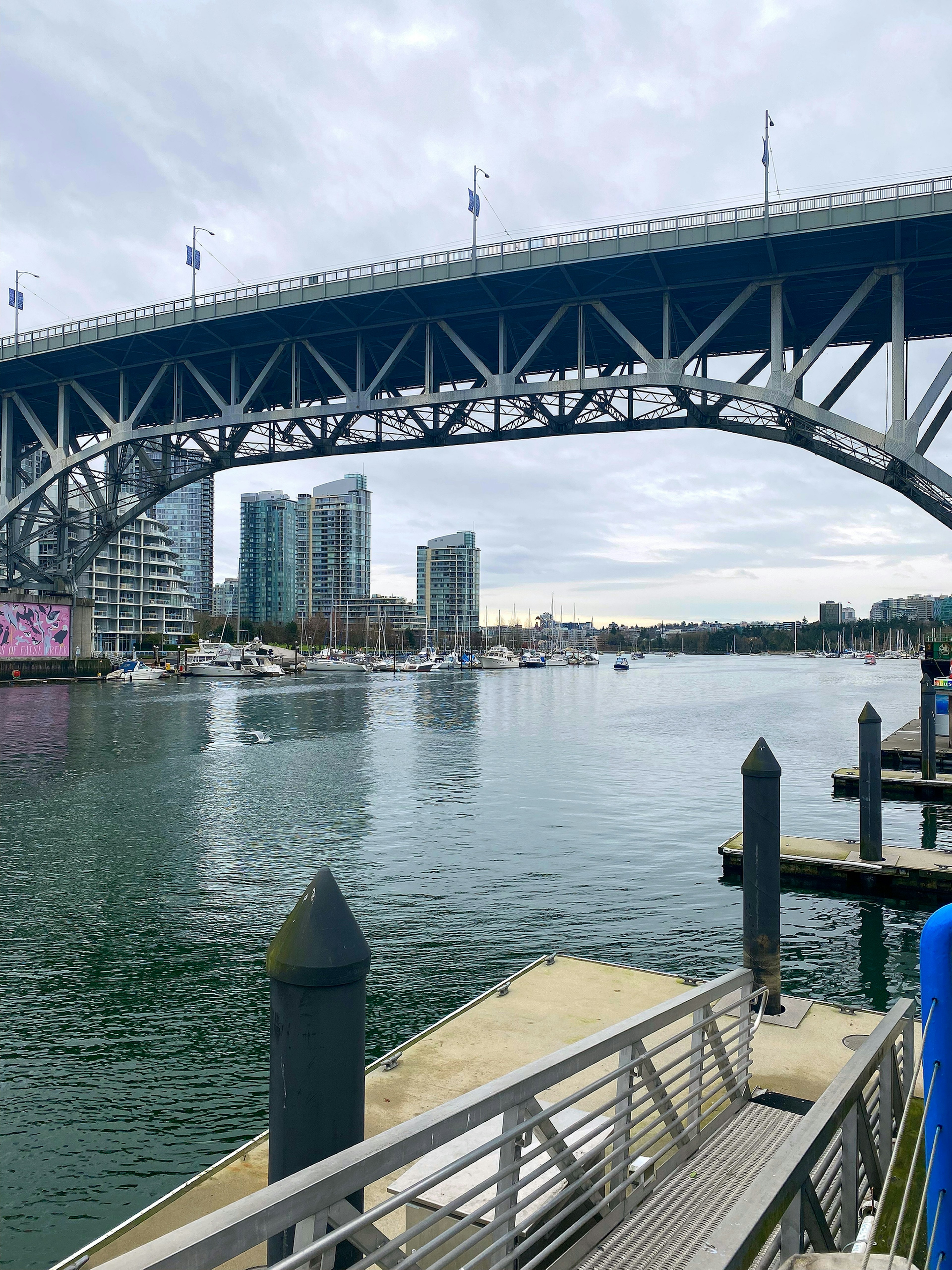 Calm water beneath a blue bridge with skyscrapers in the background