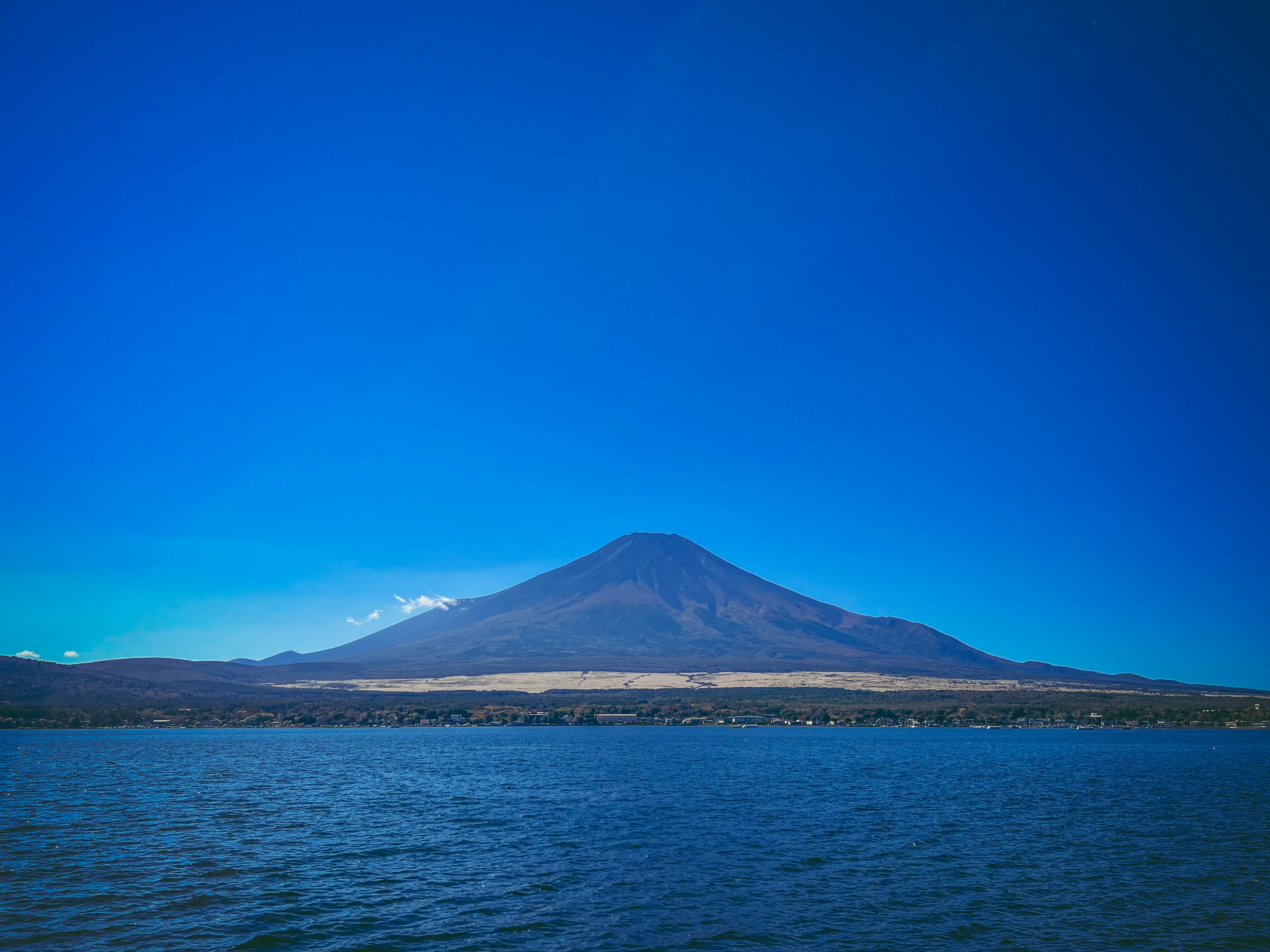 Pemandangan pegunungan yang indah menjulang di atas danau di bawah langit biru