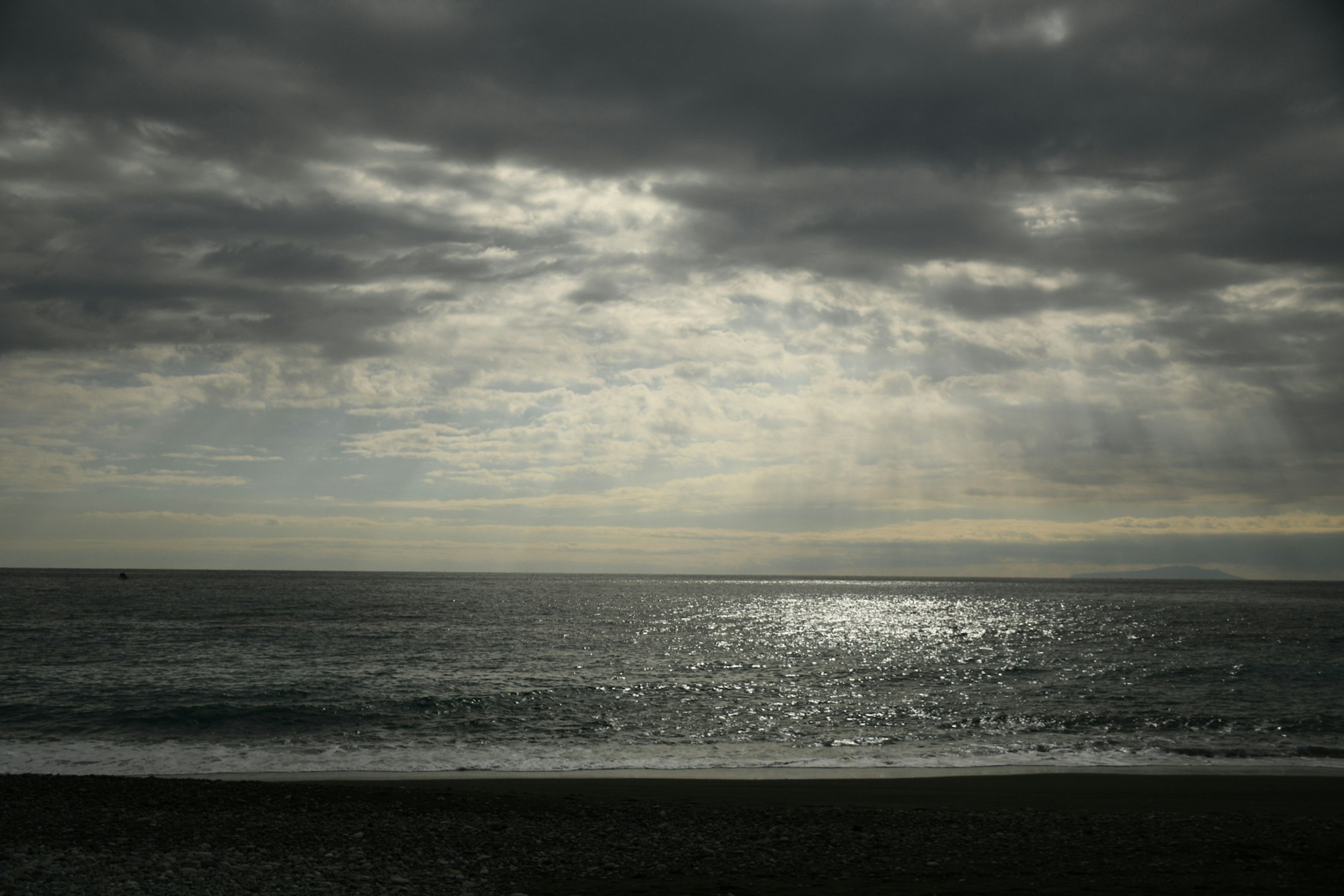 曇り空の海の風景波の上に反射する光