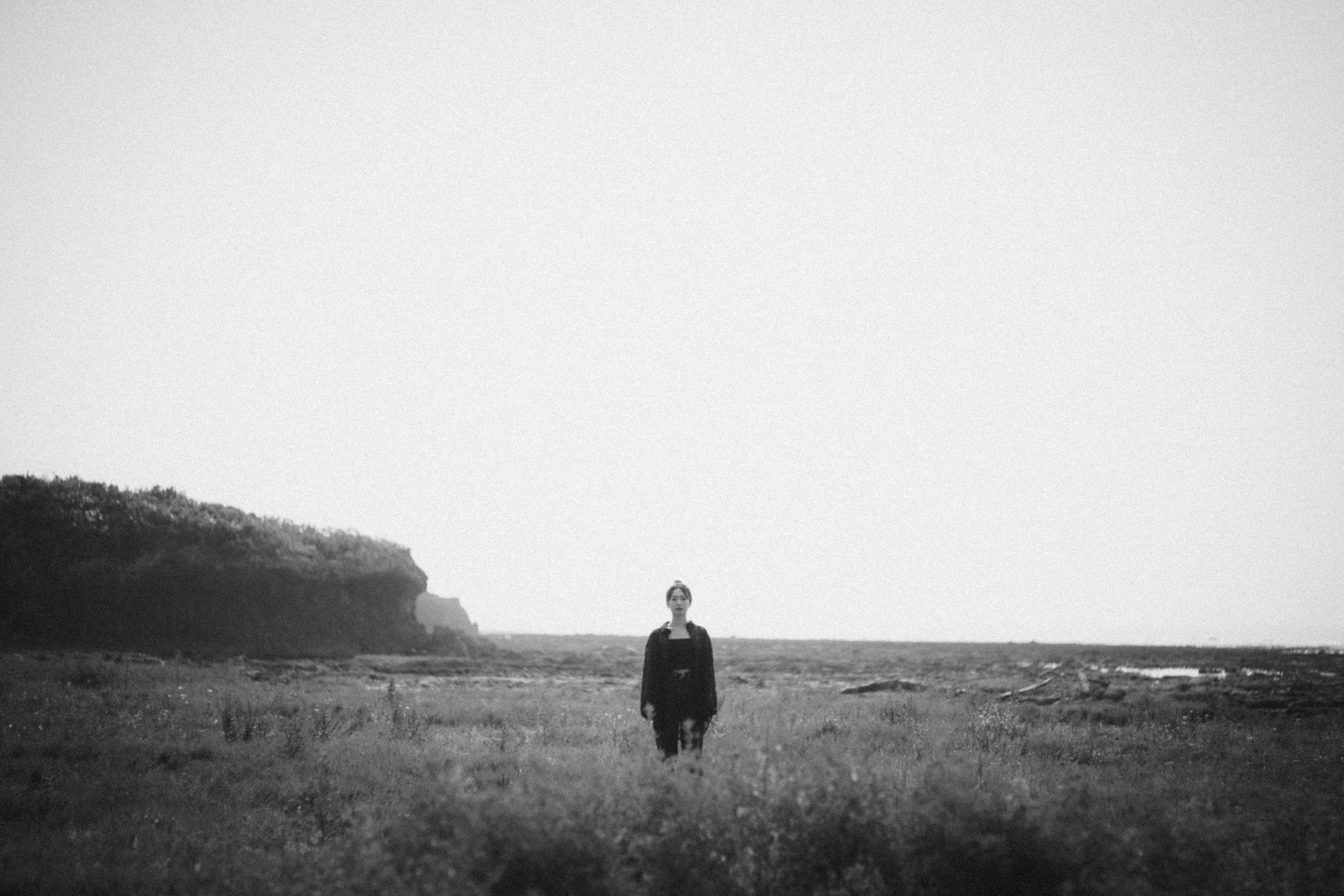 A person standing in a vast grassland in a black and white landscape