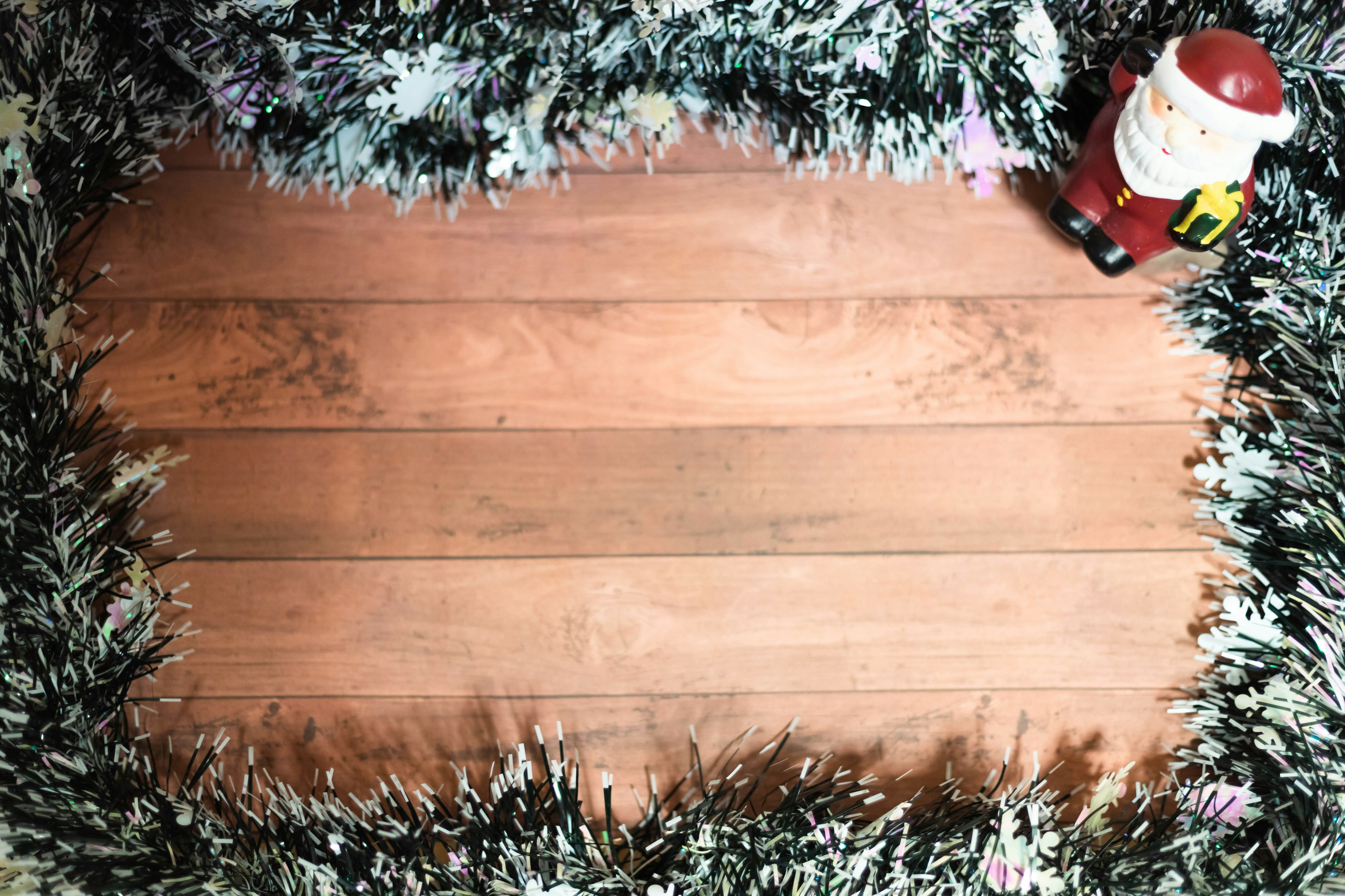 Santa Claus figurine next to green decorations on wooden planks