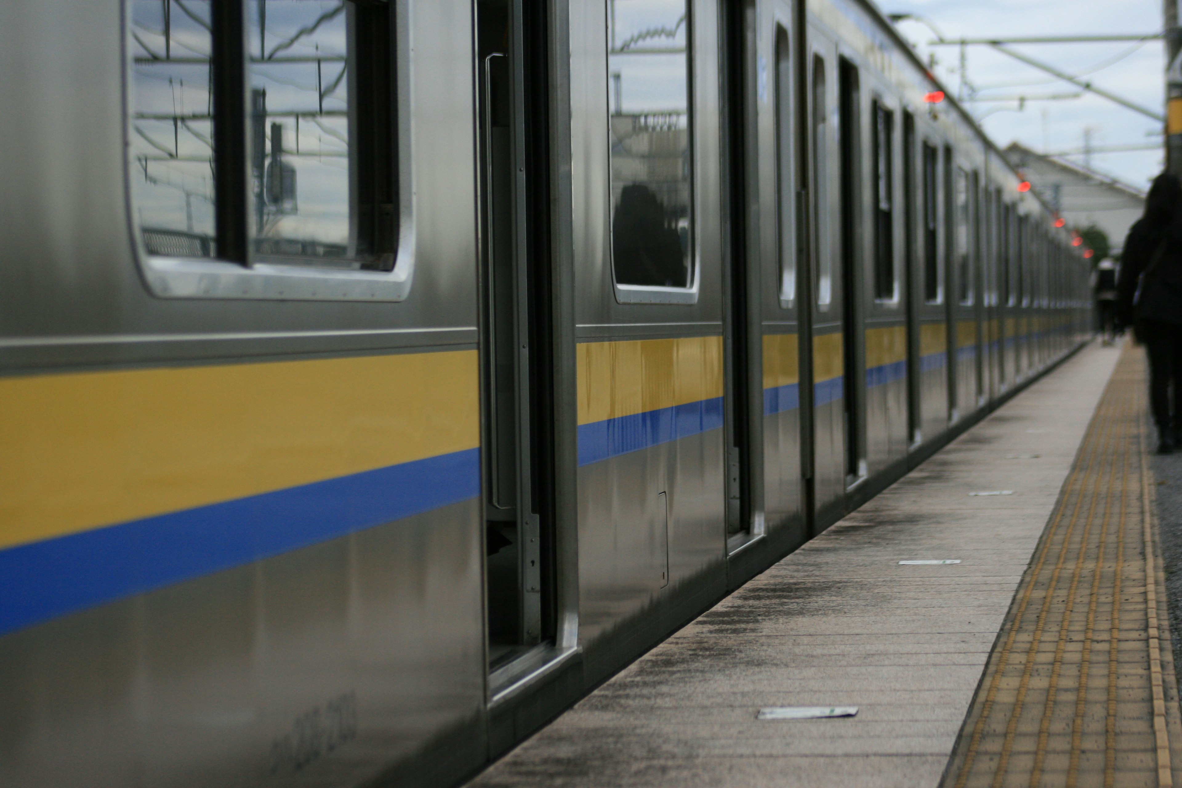 A train with blue and yellow stripes parked at a station platform