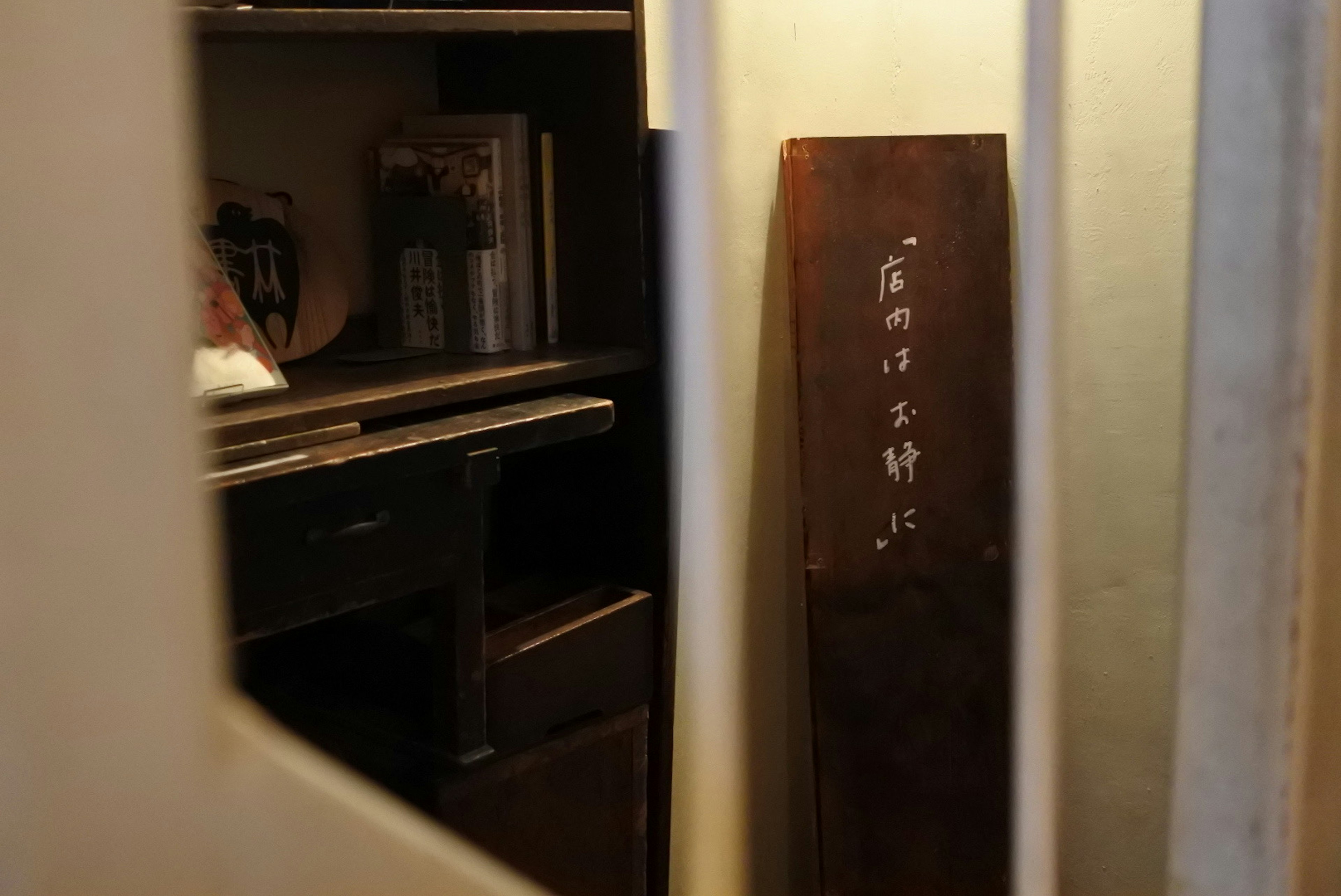 View of a room through a gap showing a wooden board with inscriptions