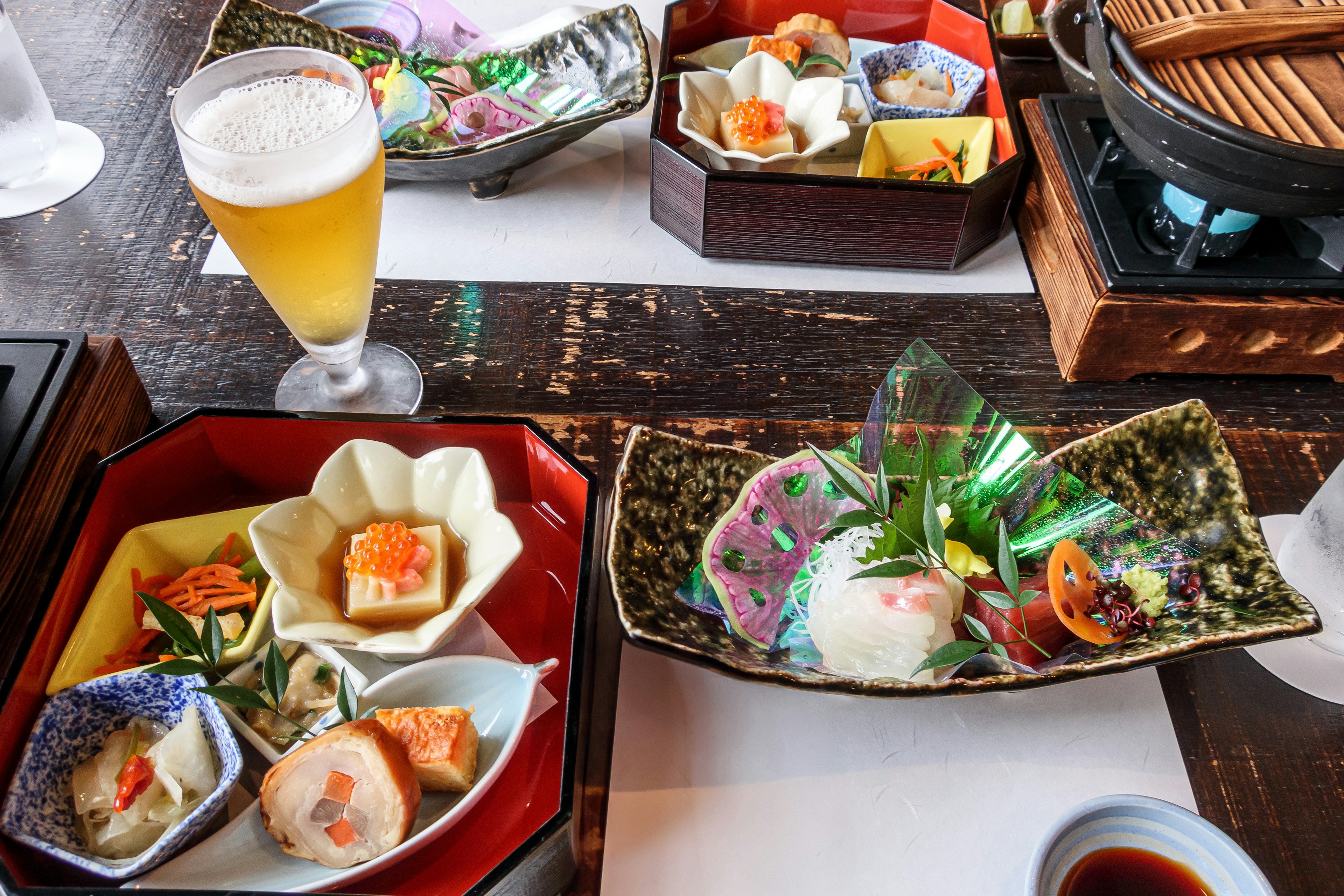 Cuisine japonaise colorée présentée sur des assiettes avec un verre de bière