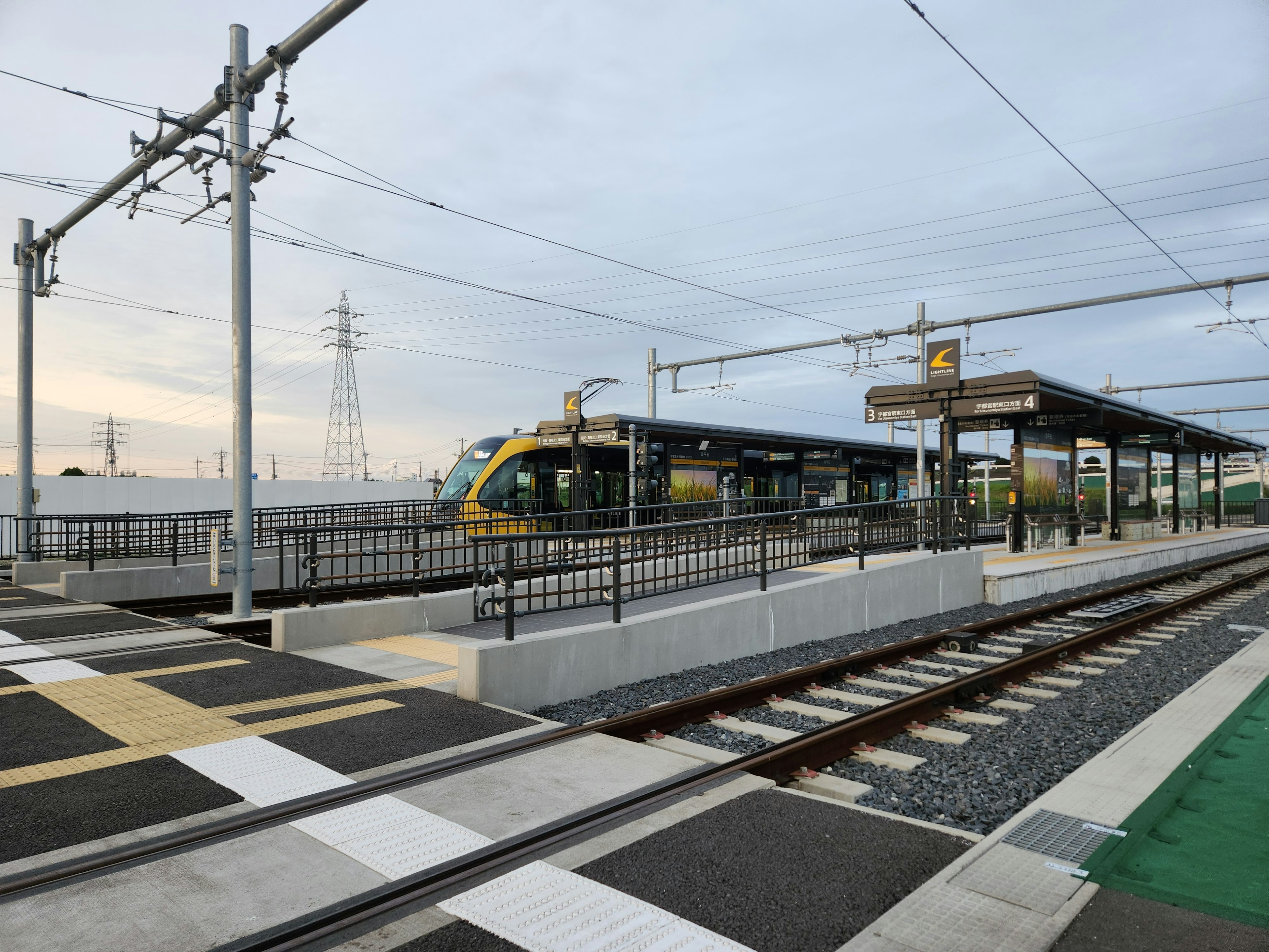 New train station with a train visible along the tracks and platform