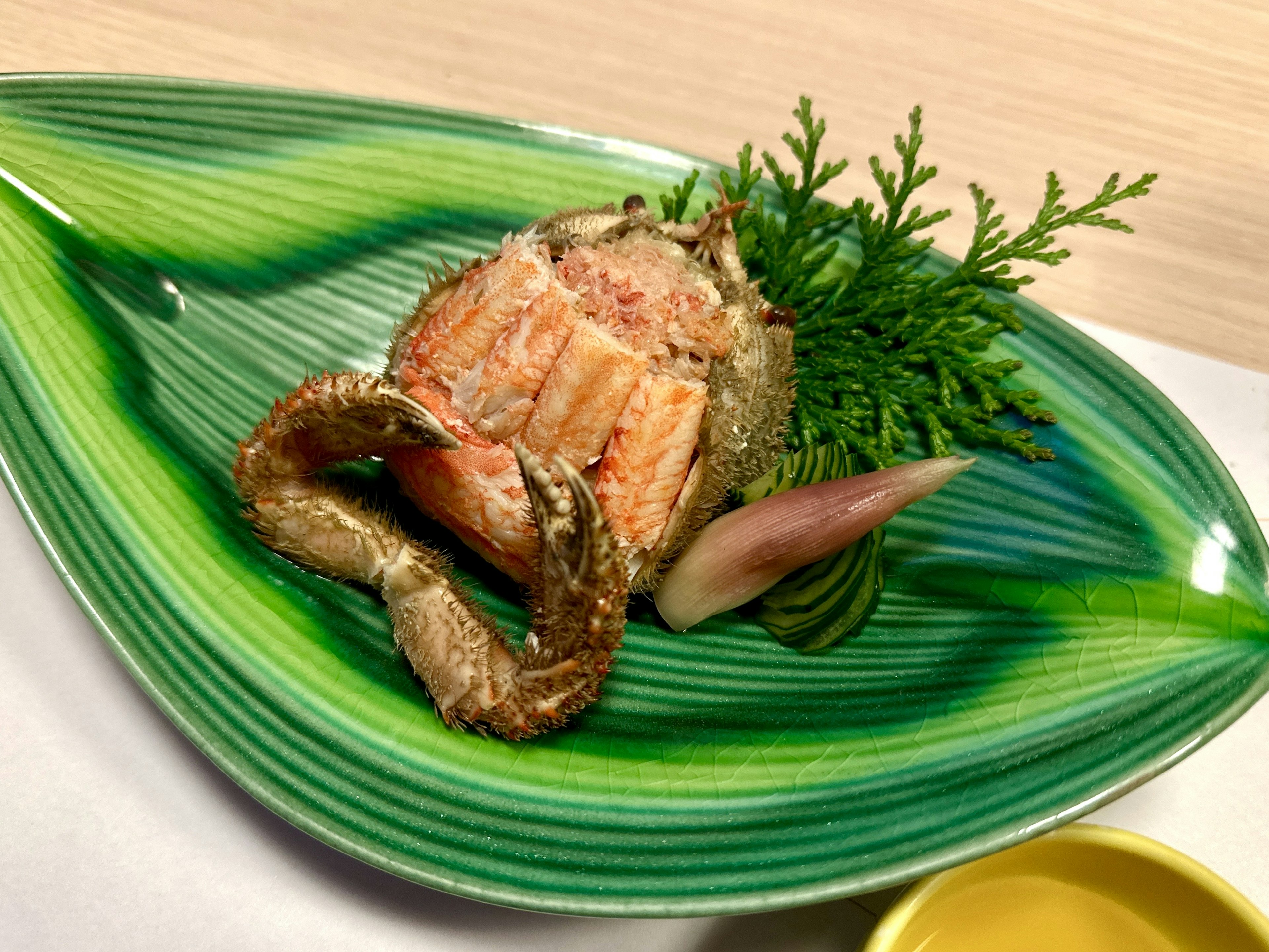 Crab dish served on a green leaf-shaped plate with fresh herbs