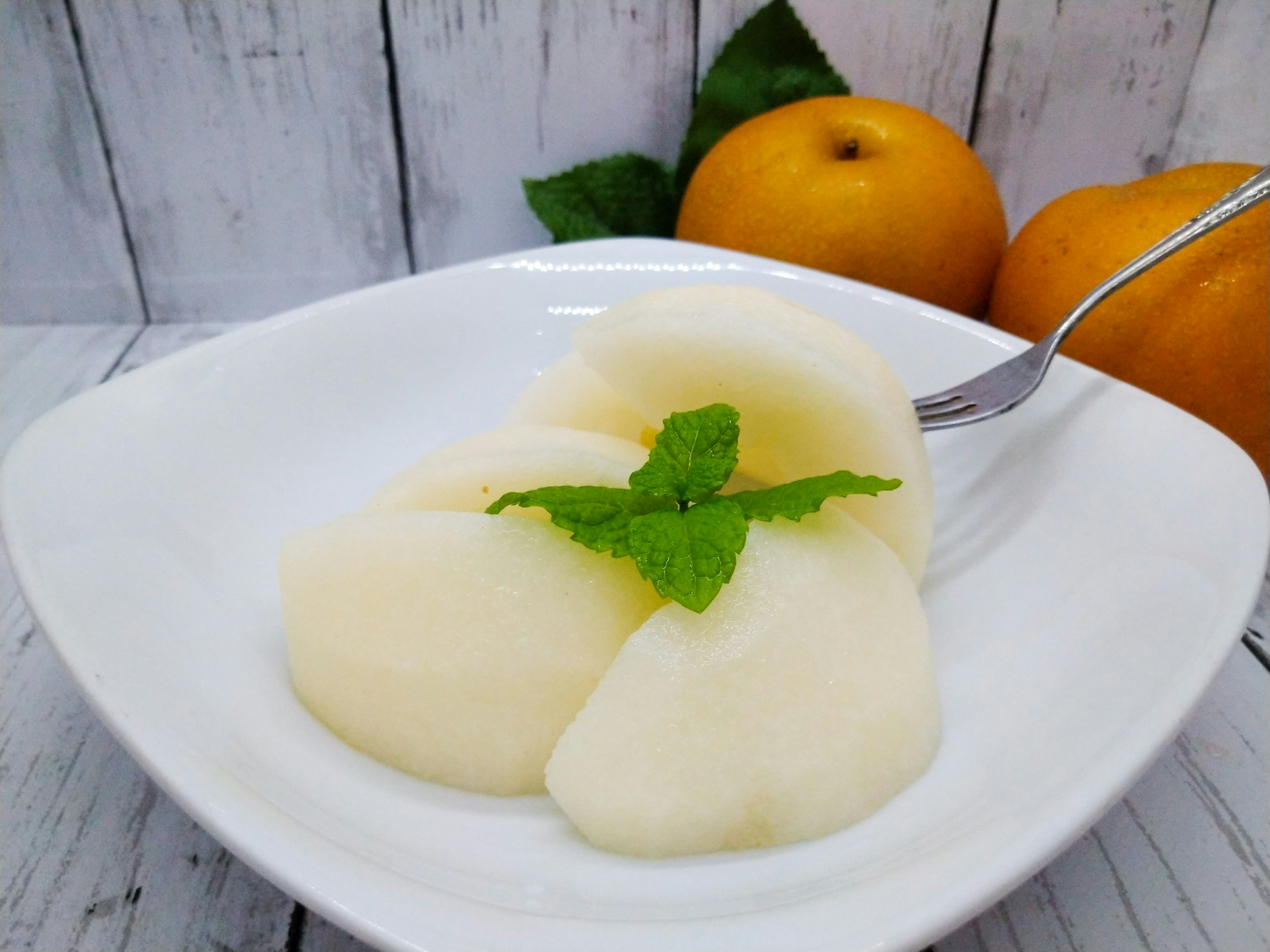 Purè di frutta liscio servito in una ciotola bianca con una foglia di menta come guarnizione