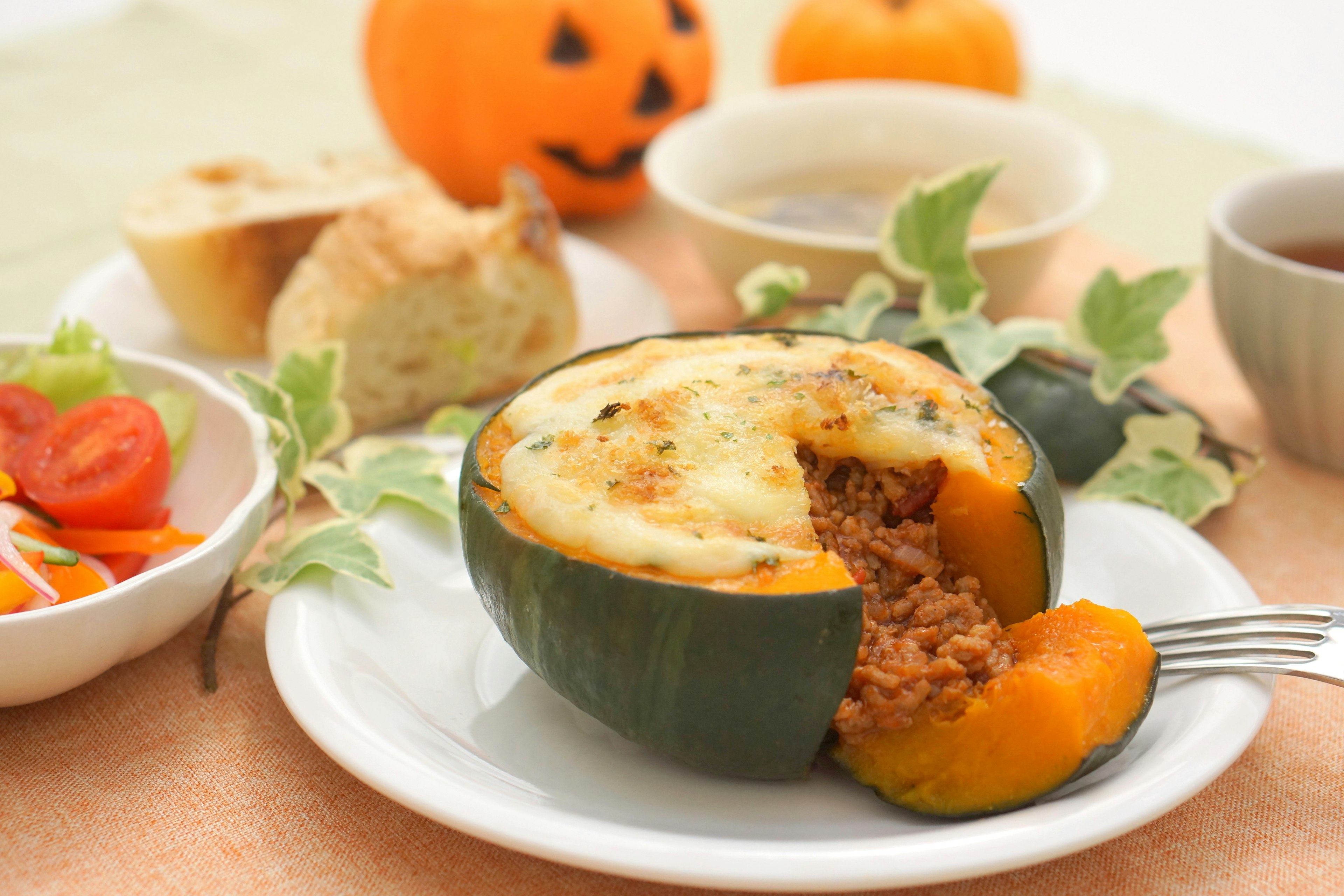 Un tavolo con un piatto di zucca di Halloween e insalata