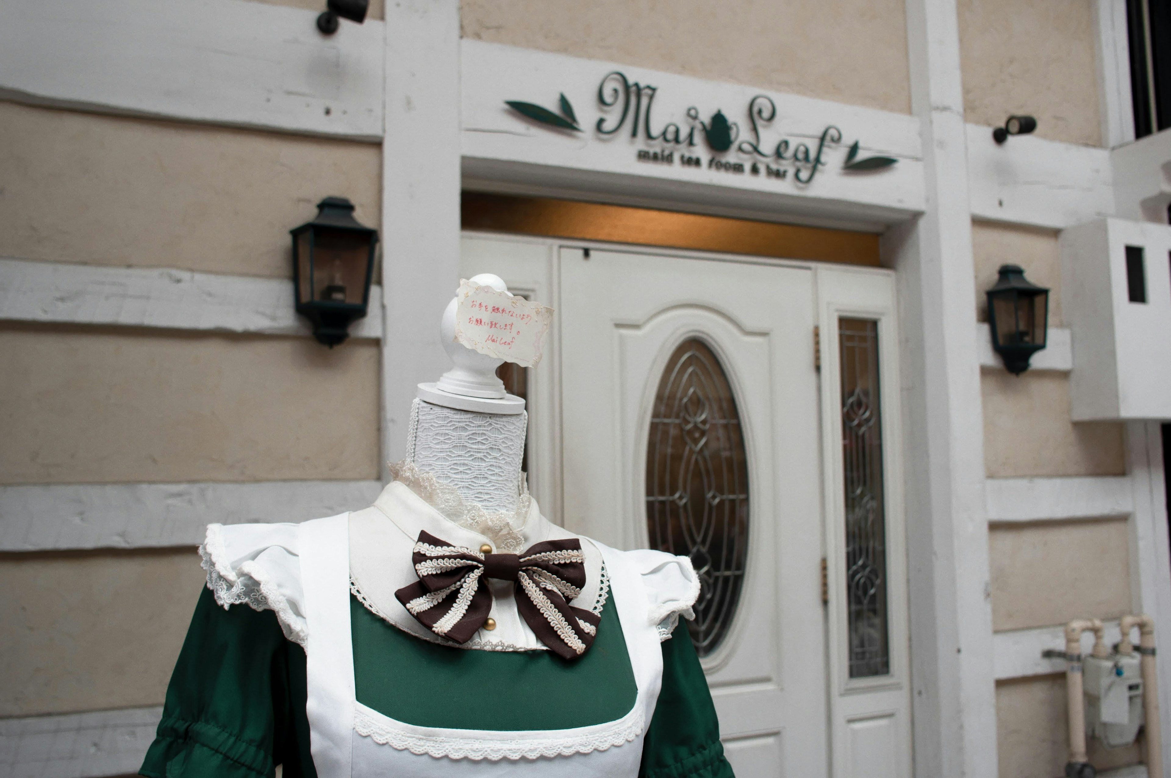 Maniquí con vestido verde y moño afuera de un café