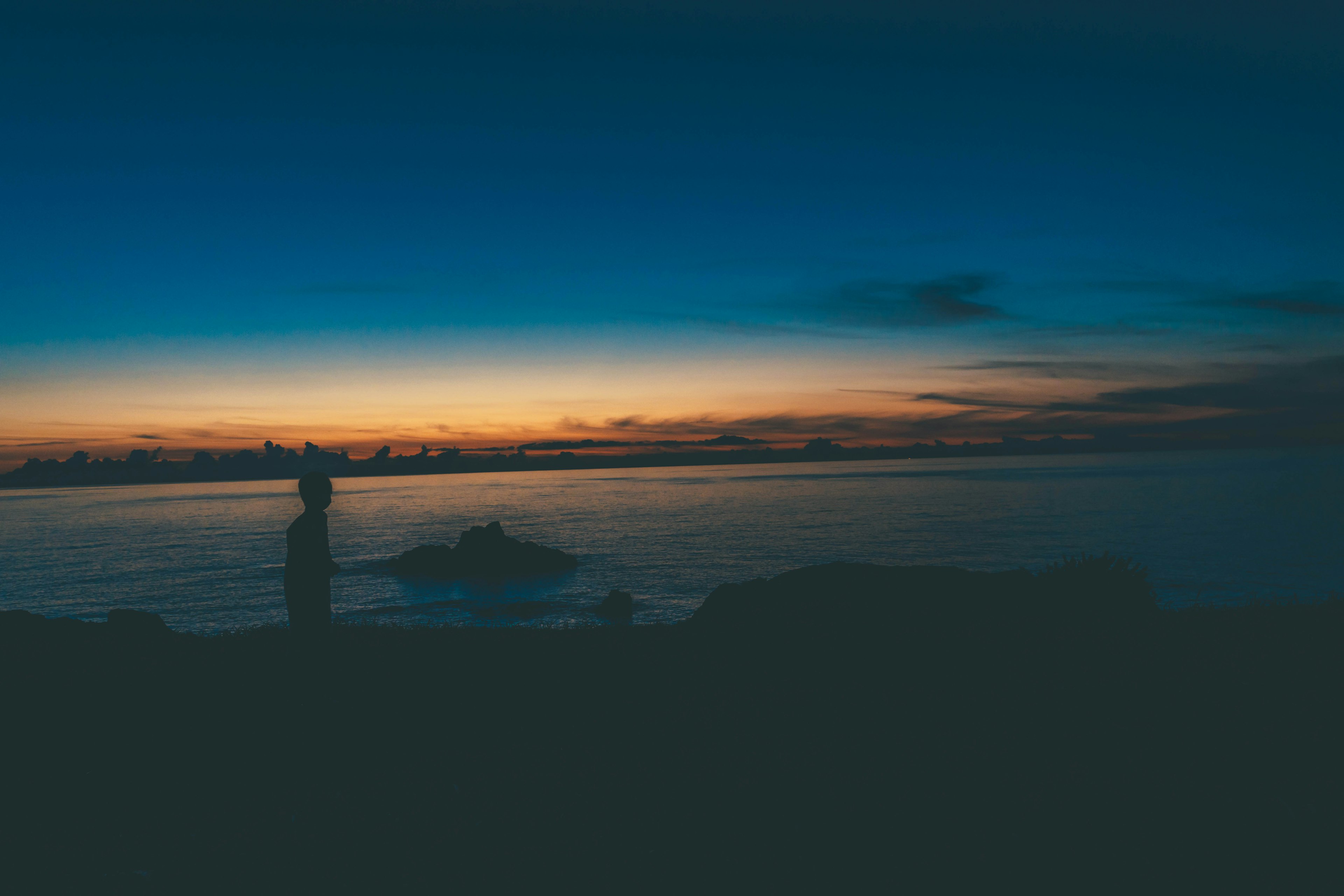 Silhouette einer Person gegen einen Sonnenuntergang über dem Meer