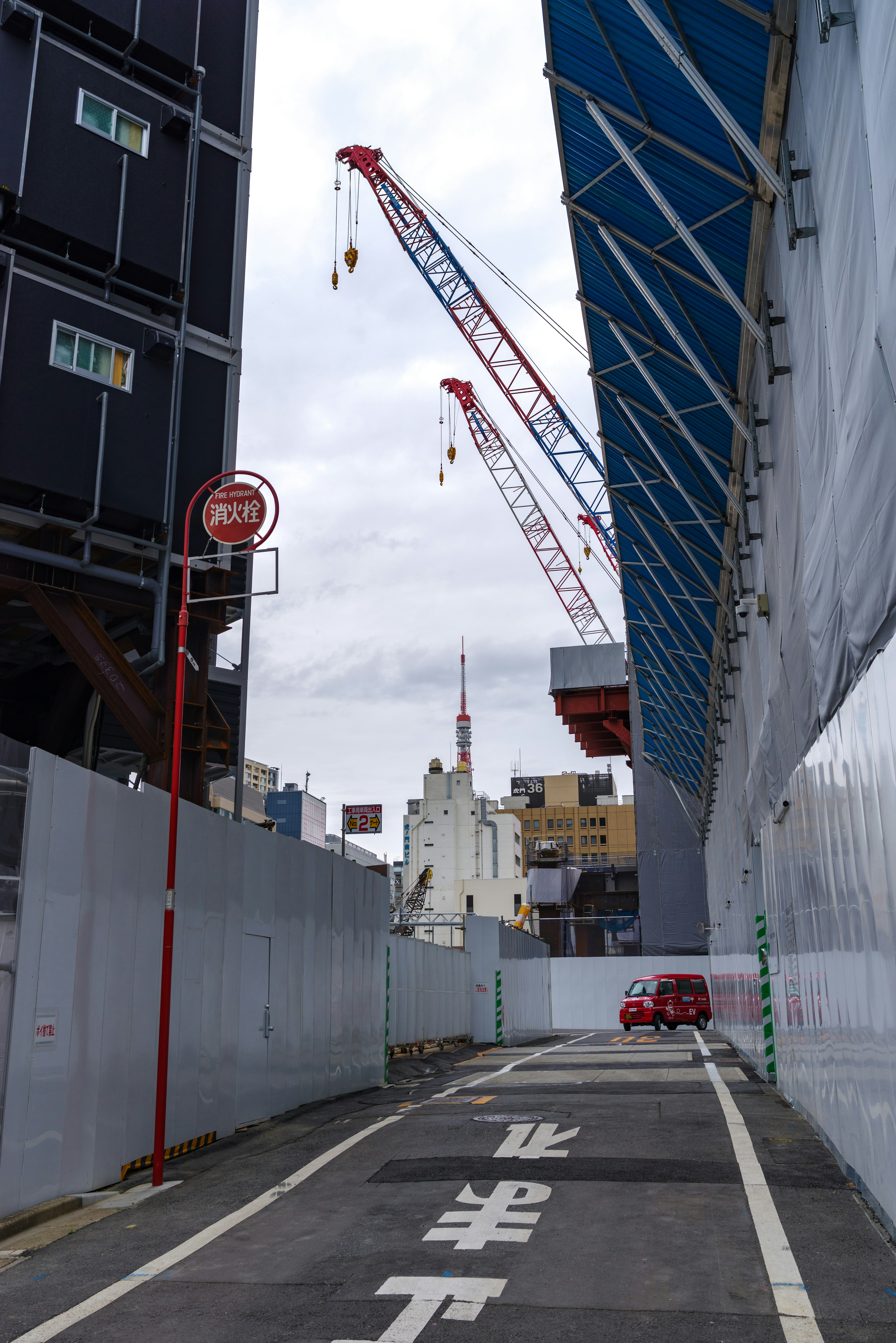 Street view of a construction site with cranes and a blue roof