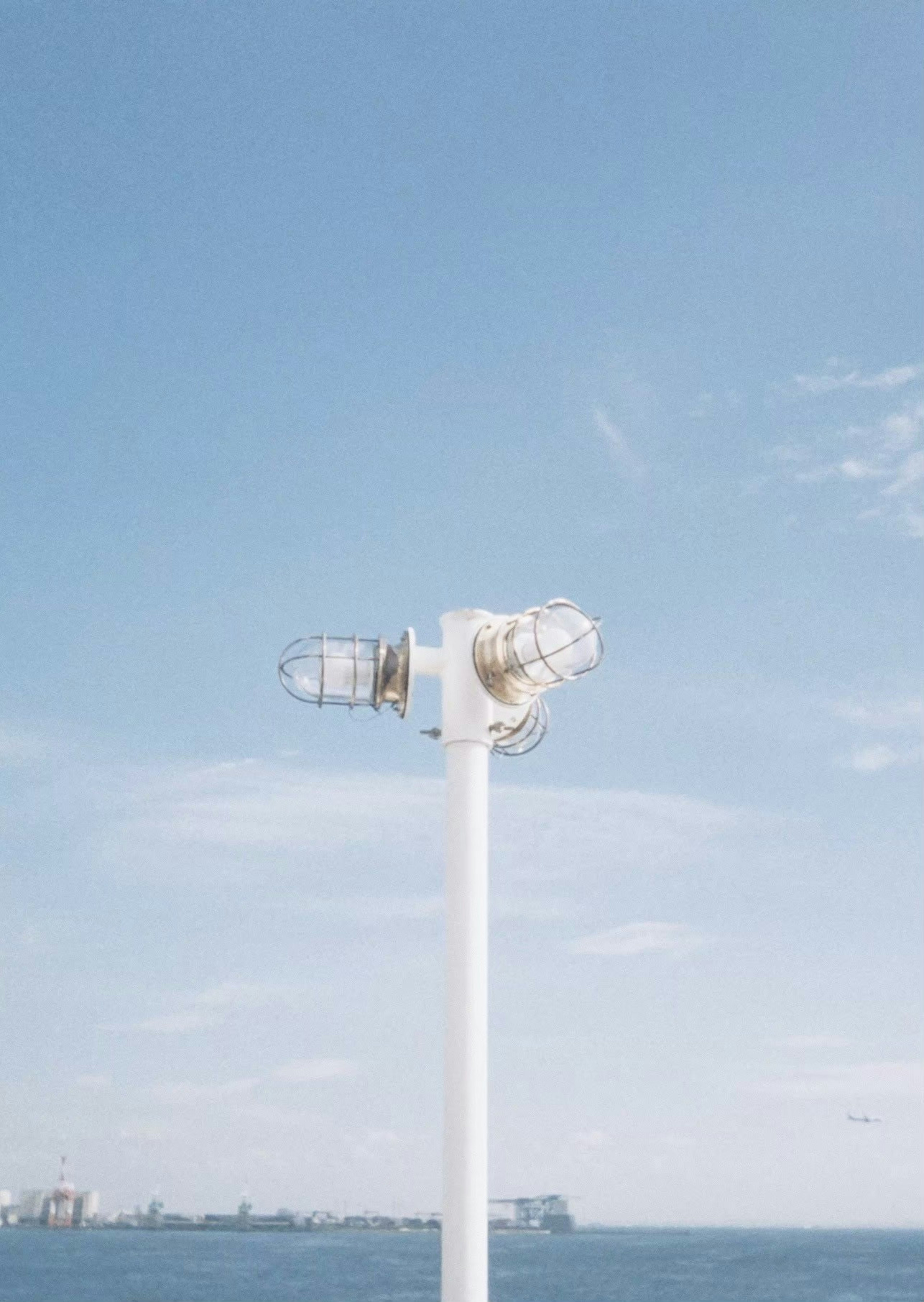 Faro blanco contra un cielo azul y el mar