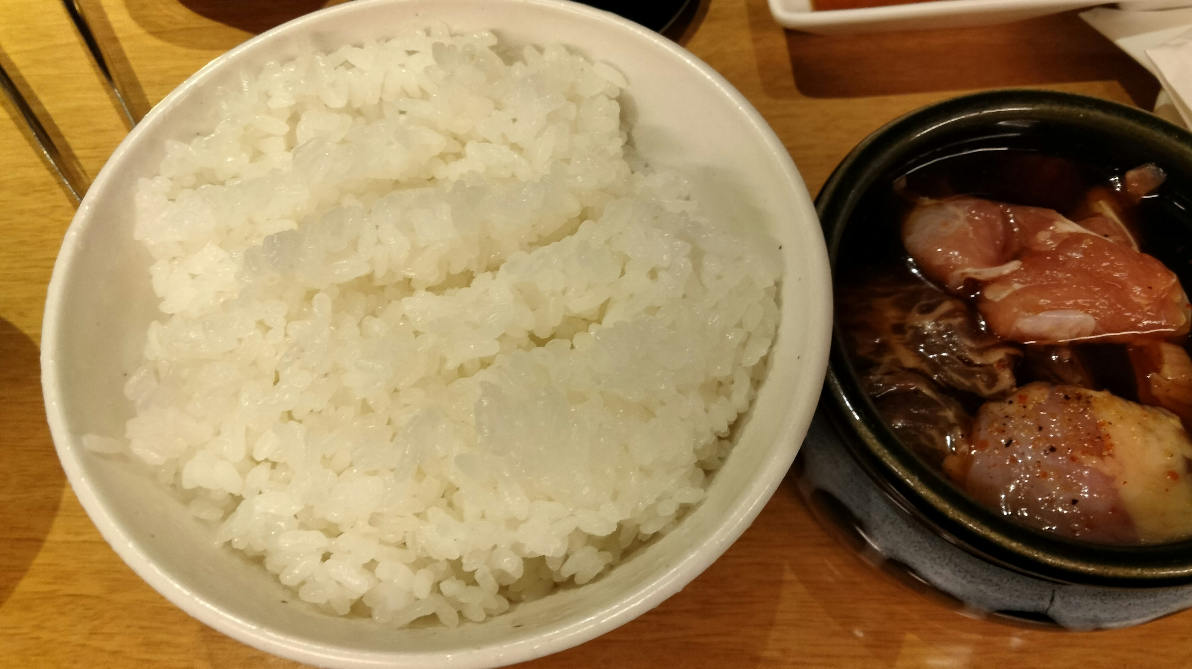 Un tazón de arroz blanco junto a un plato de carne en salsa