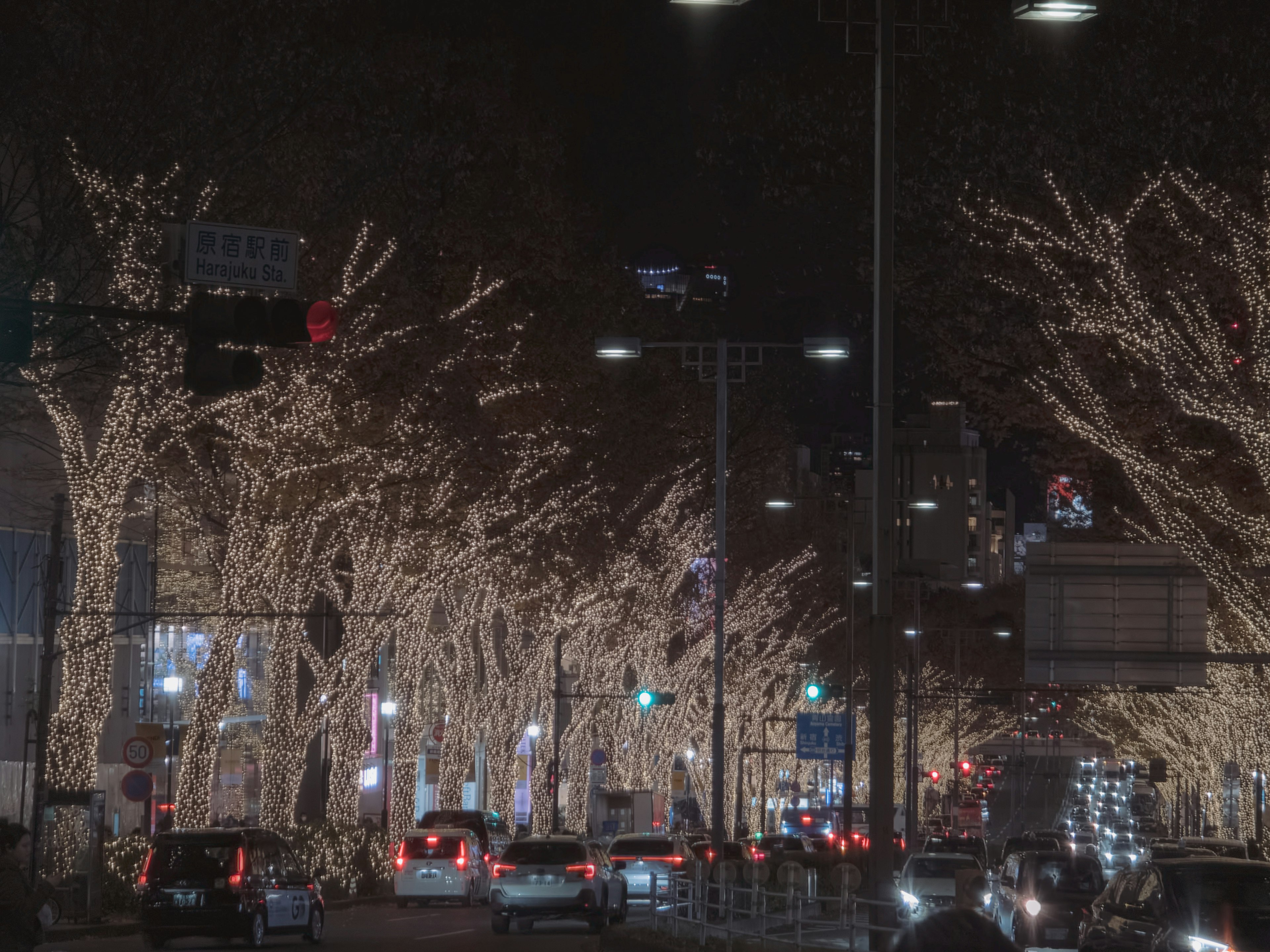 Calle nocturna adornada con luces centelleantes y coches en movimiento