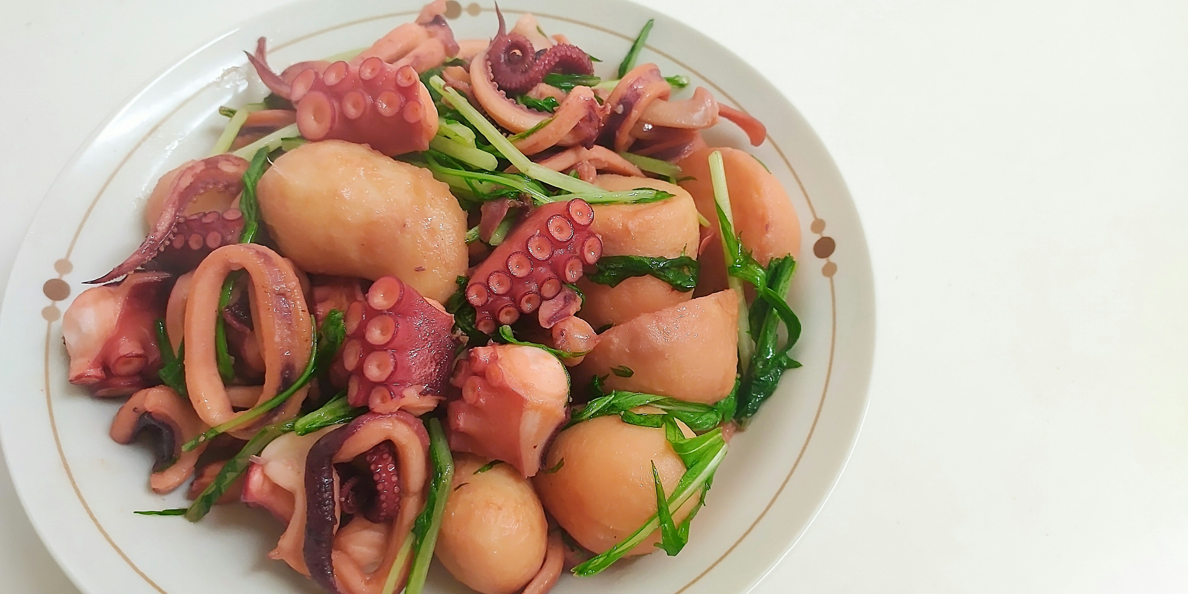 Un piatto di polpo e calamaro guarnito con verdure verdi fresche