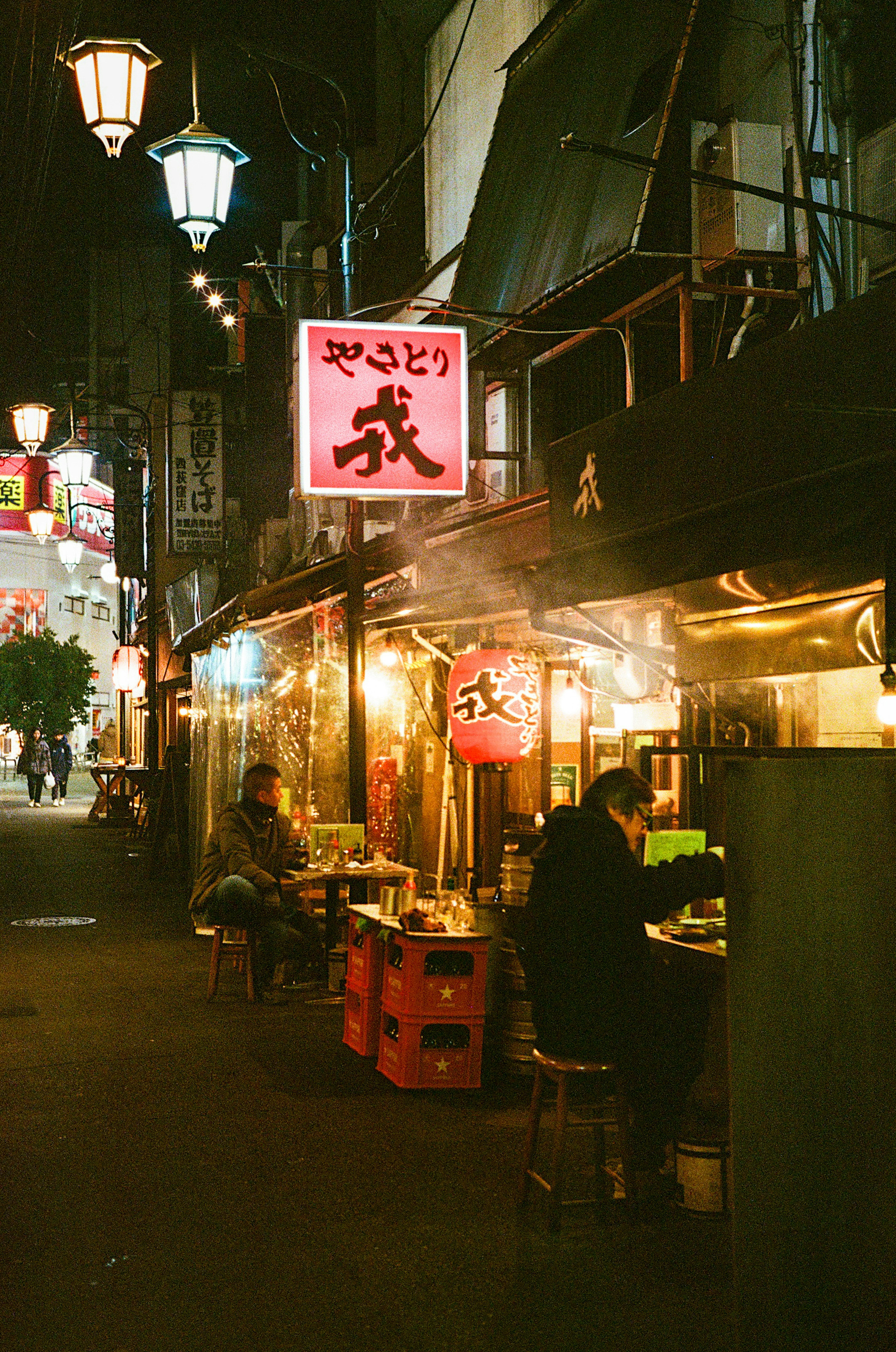 Puestos de comida callejera de noche con letreros brillantes