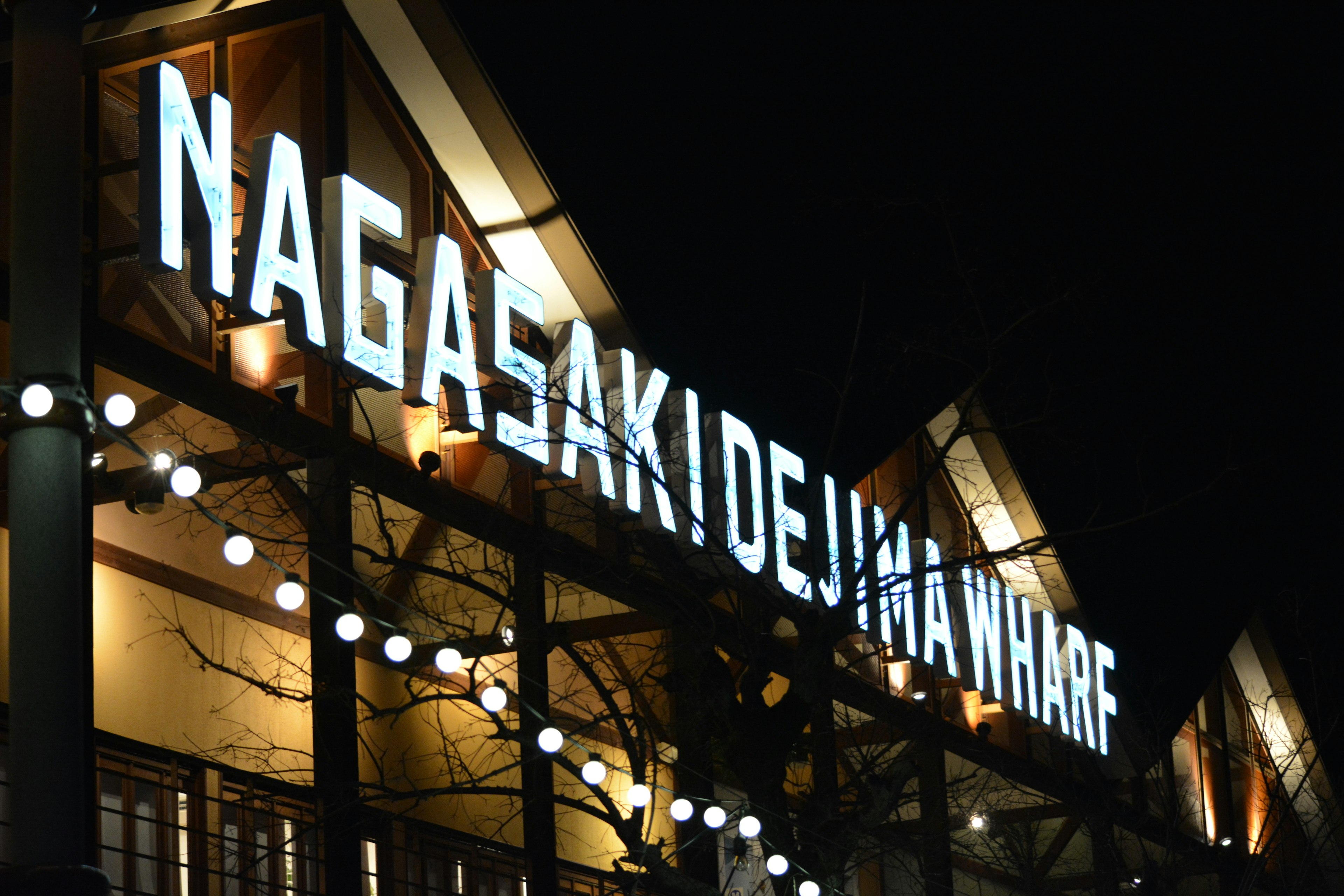 Nachtansicht des Dejima-Hafens in Nagasaki mit beleuchtetem Schild